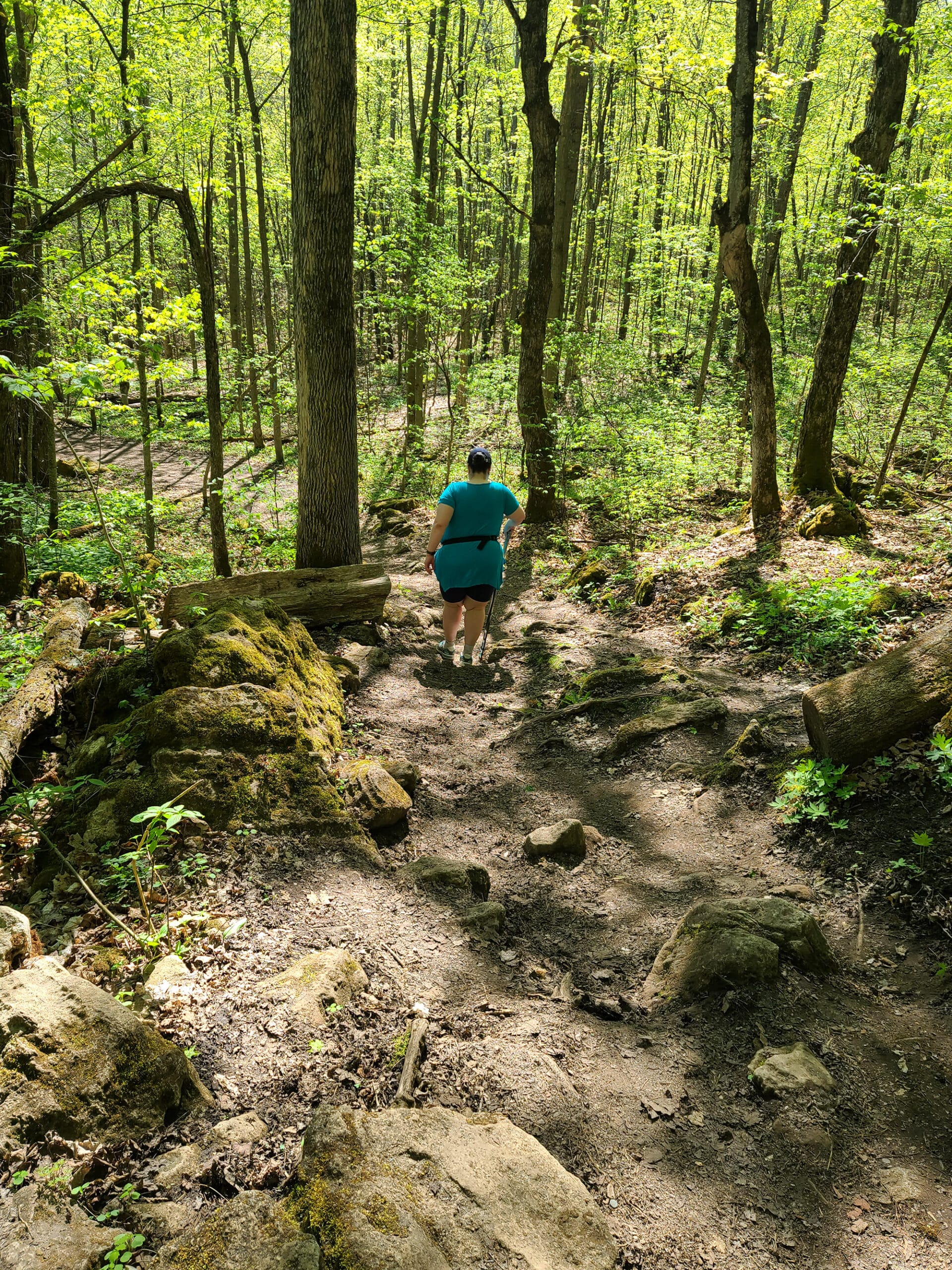 A large middle aged white woman hiking down a rocky embankment.