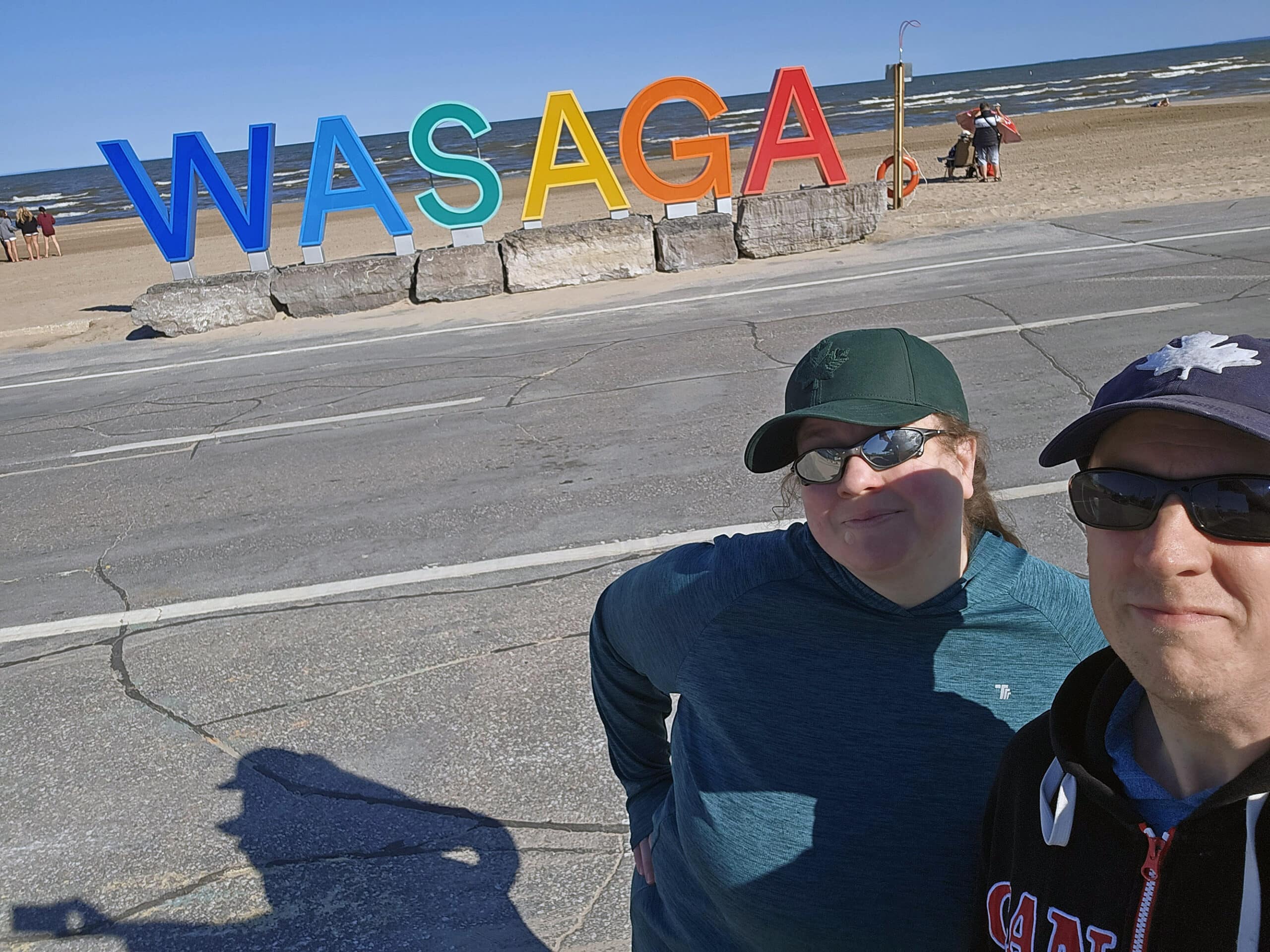 Rainbow letters spelling out wasaga, with the authors taking a selfie in front of it.
