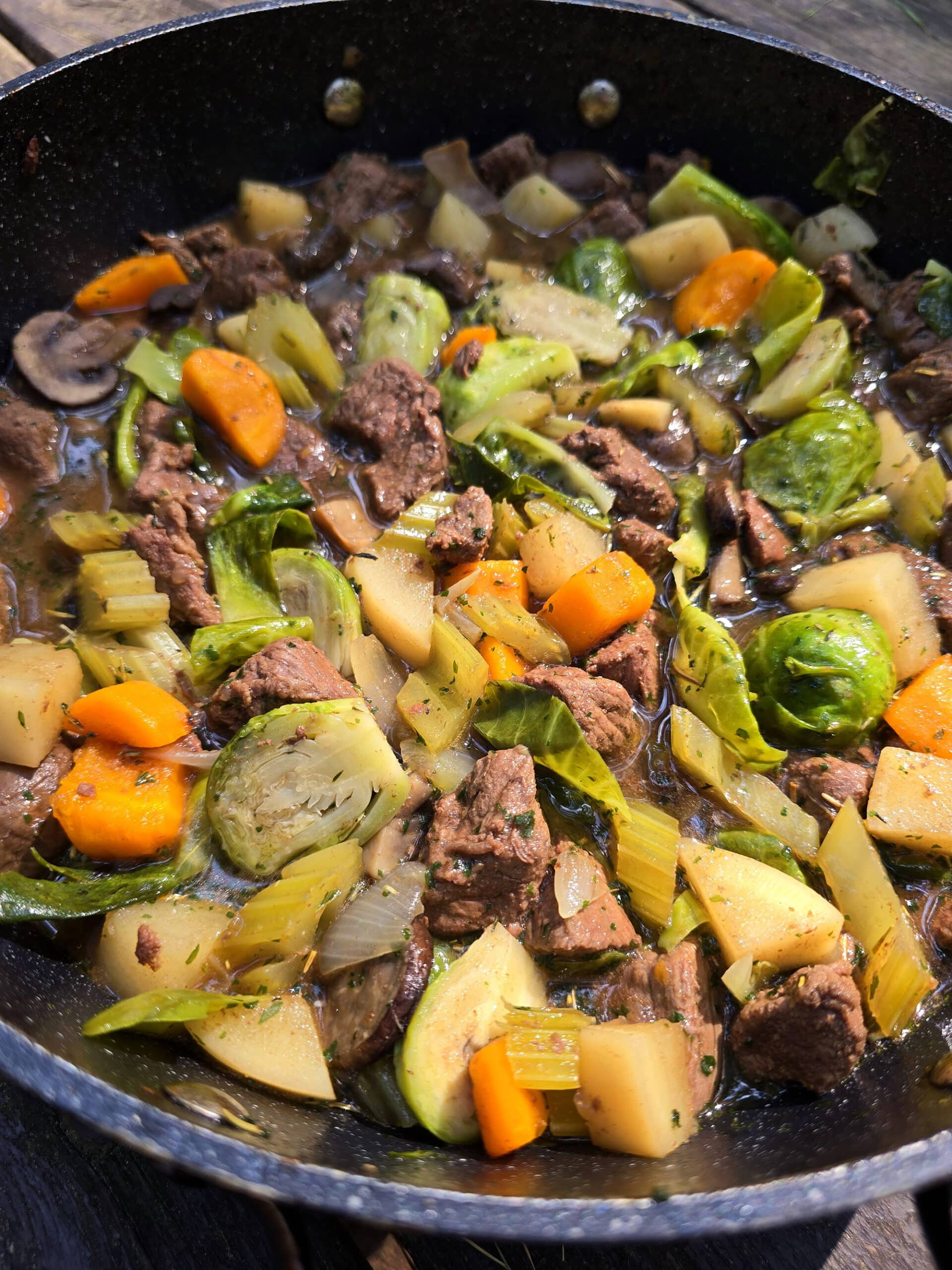 A large pot of stew over a charcoal BBQ.