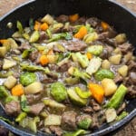 A large pot of campfire stew over a charcoal BBQ.