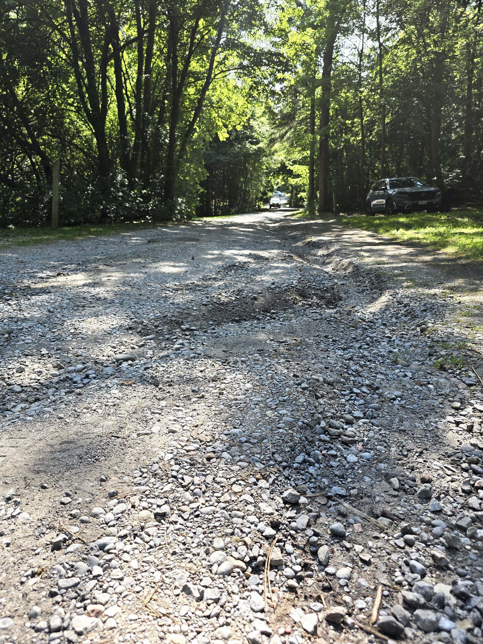 A very water damaged gravel road with deep ruts.