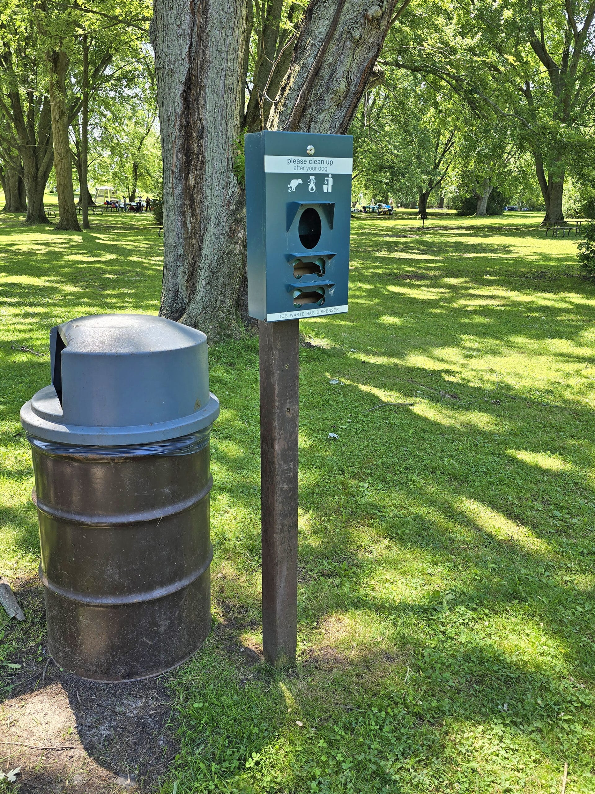 A garbage can and trail sign for dog poop bags.