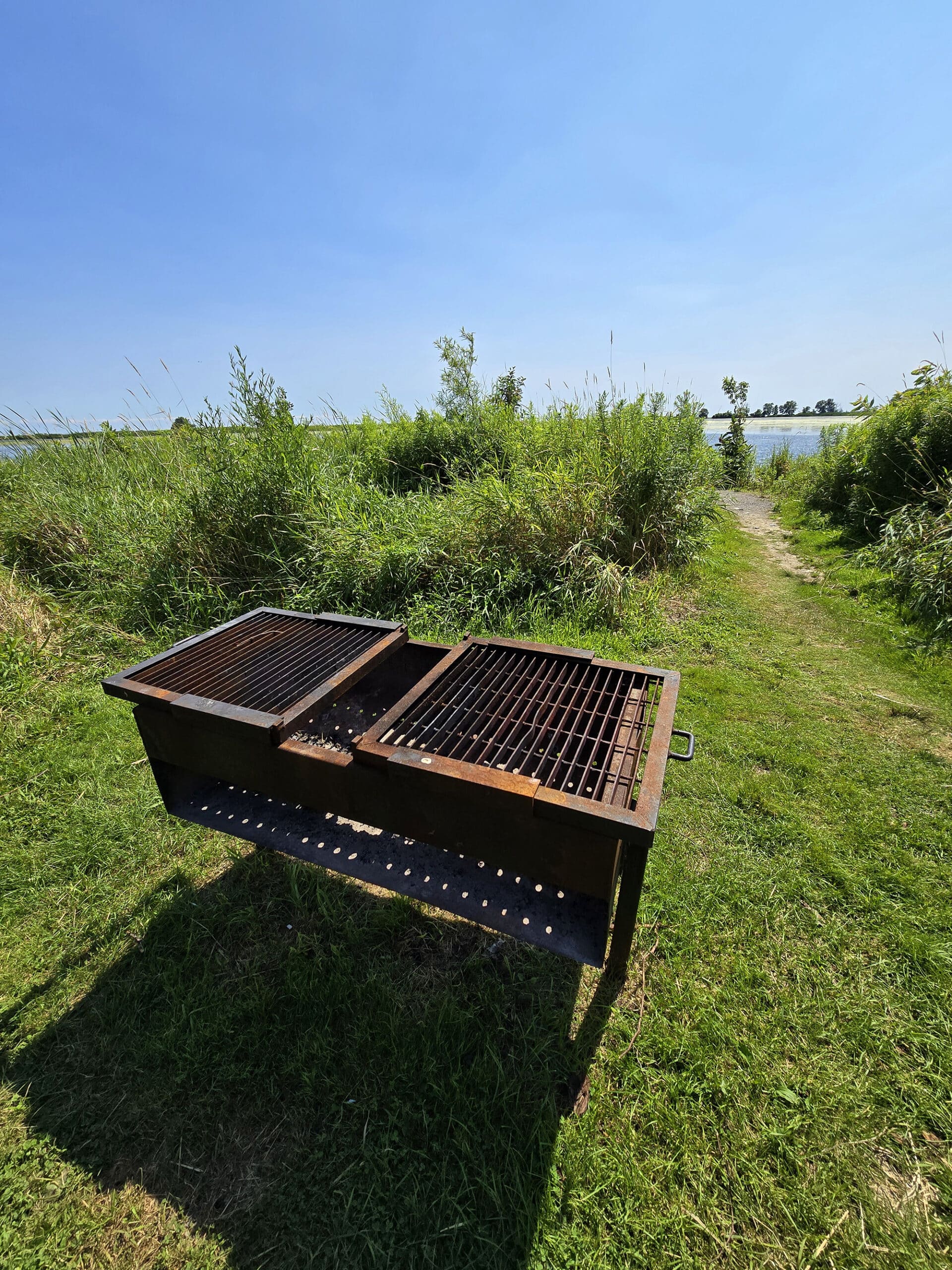 A large outdoor grill with mclaughlin bay in the background.