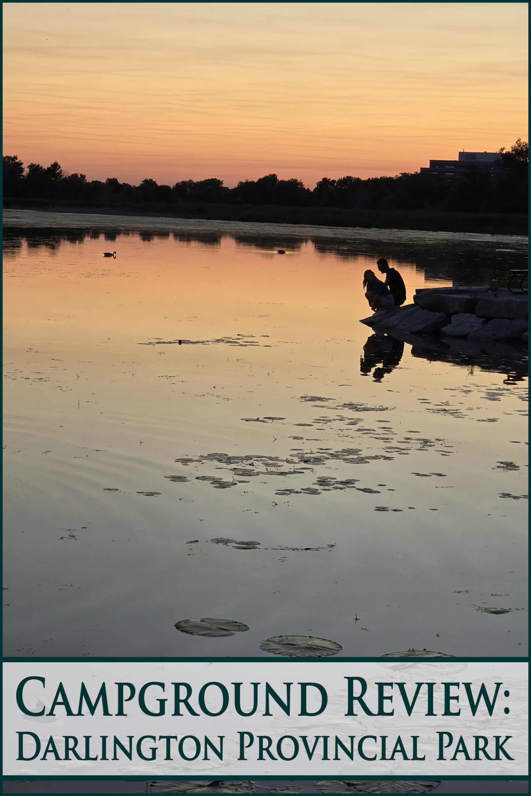 A couple on the shore of mclaughlin bay at sunset. Overlaid text says campground review darlington provincial park.