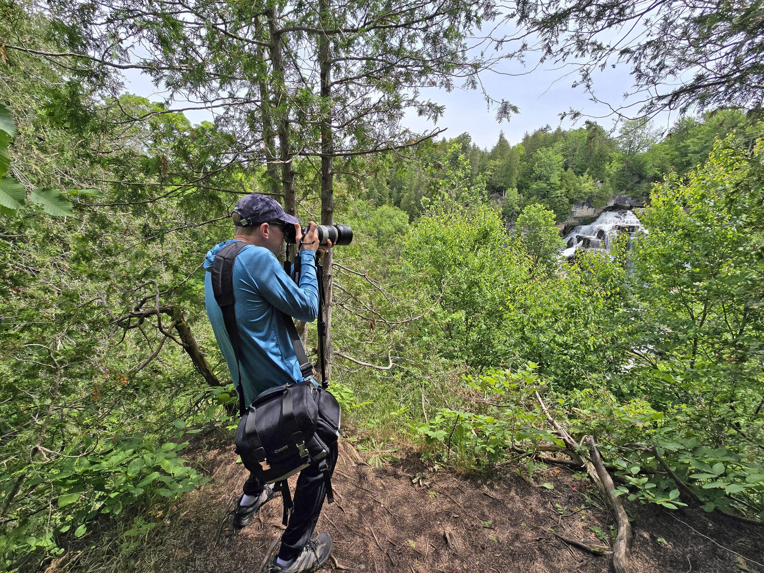 A middle aged white man taking a photo of Inglis Falls.