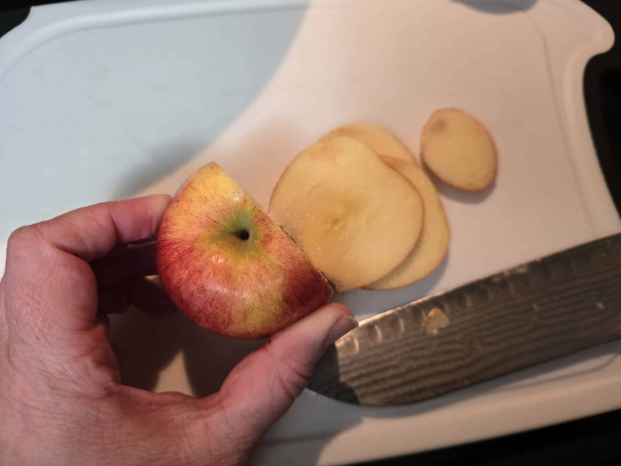 Cutting slices off one side of an apple.