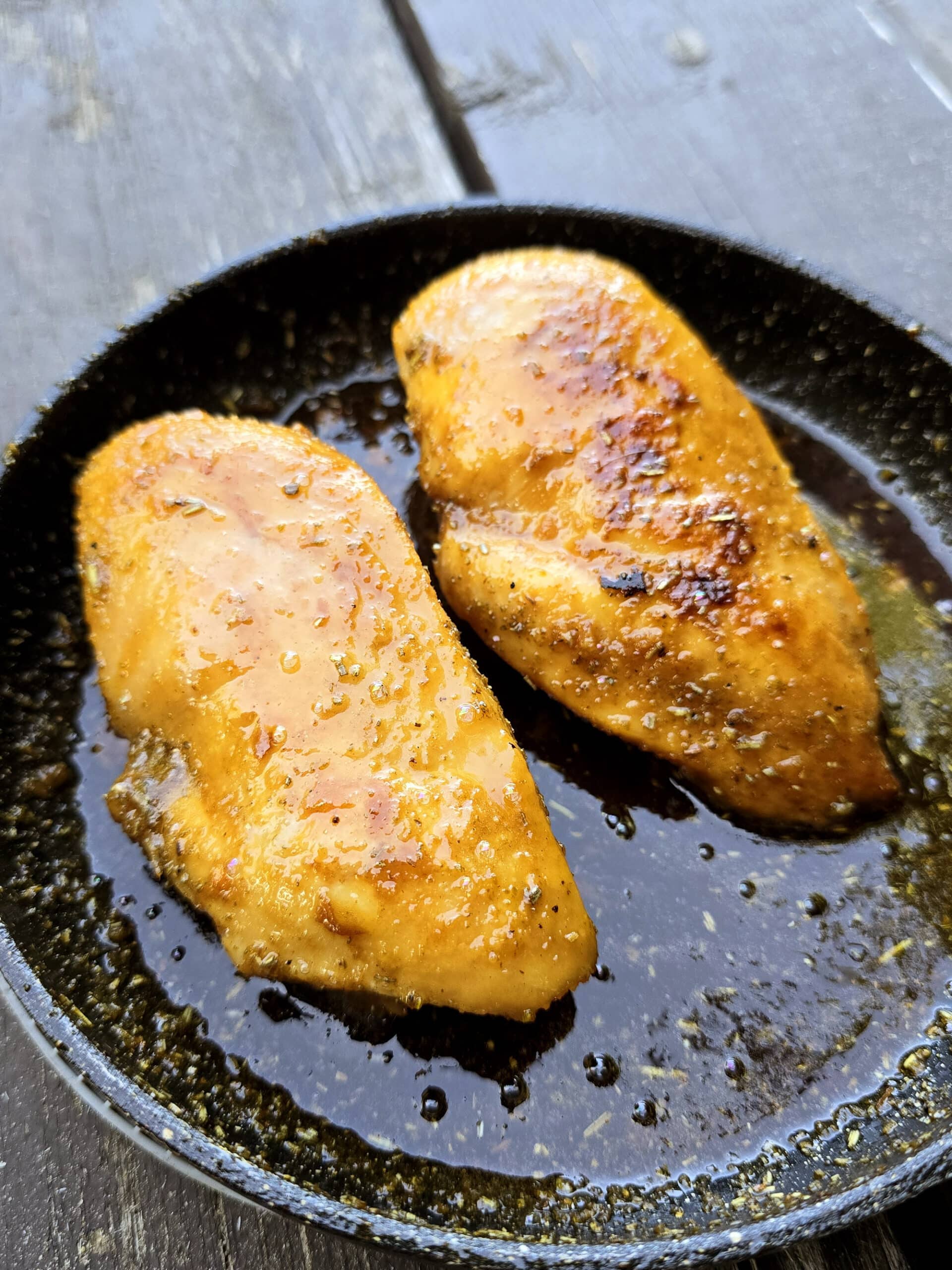 2 rosemary maple syrup glazed chicken breasts over a campfire.