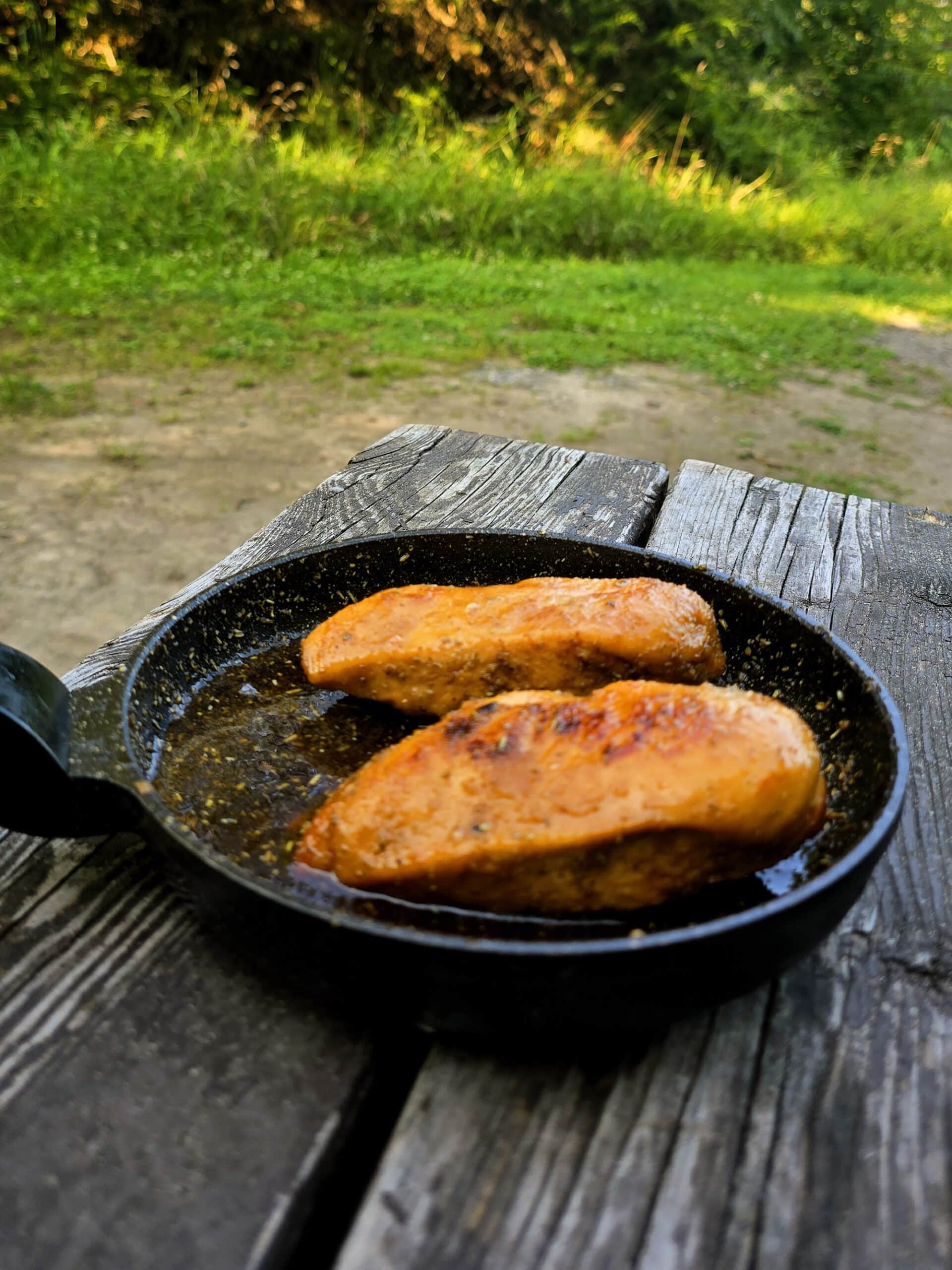 2 rosemary maple syrup chicken breasts in a pan on a picnic table.