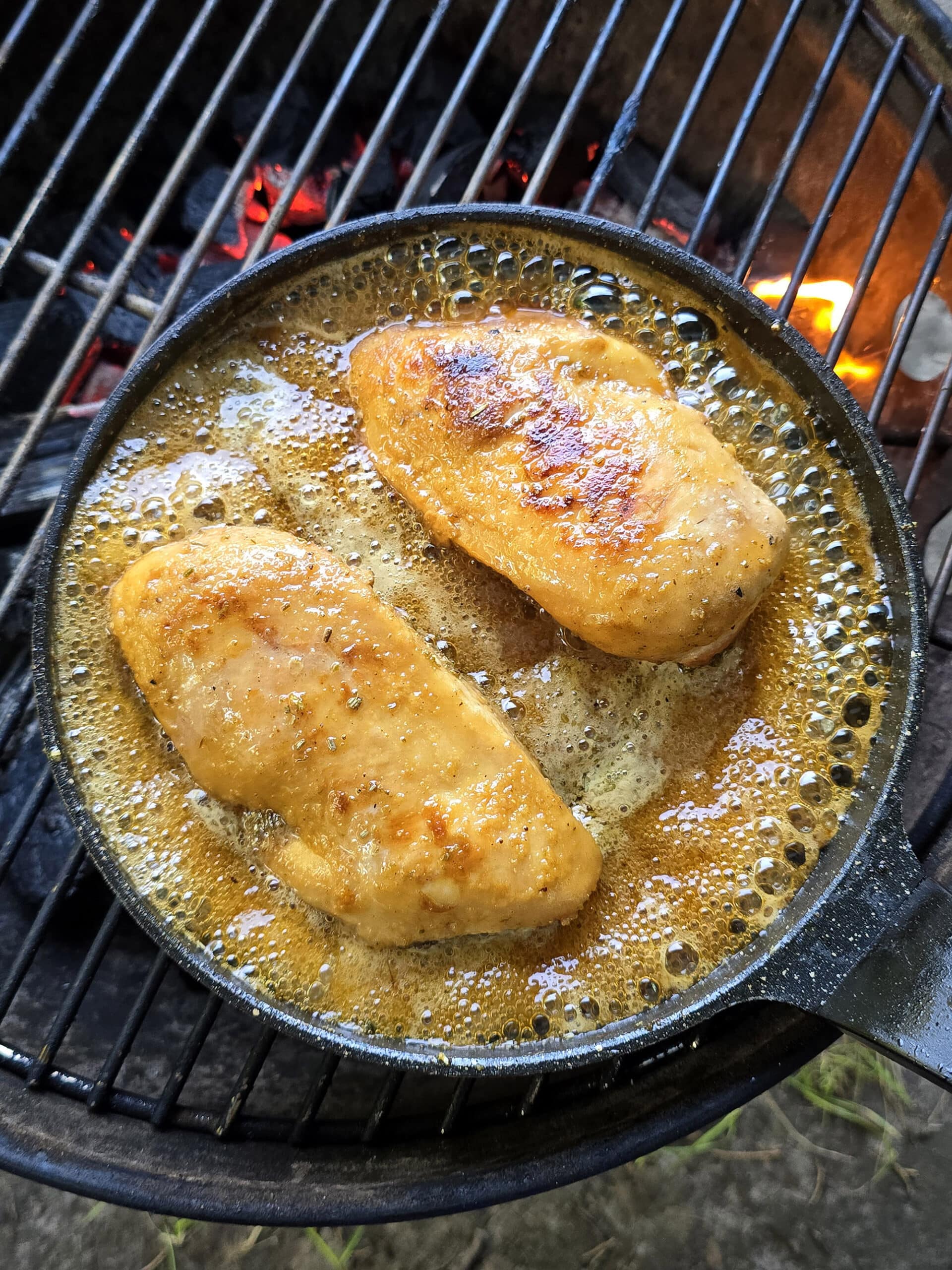 2 chicken breasts simmering in rosemary maple syrup glaze.