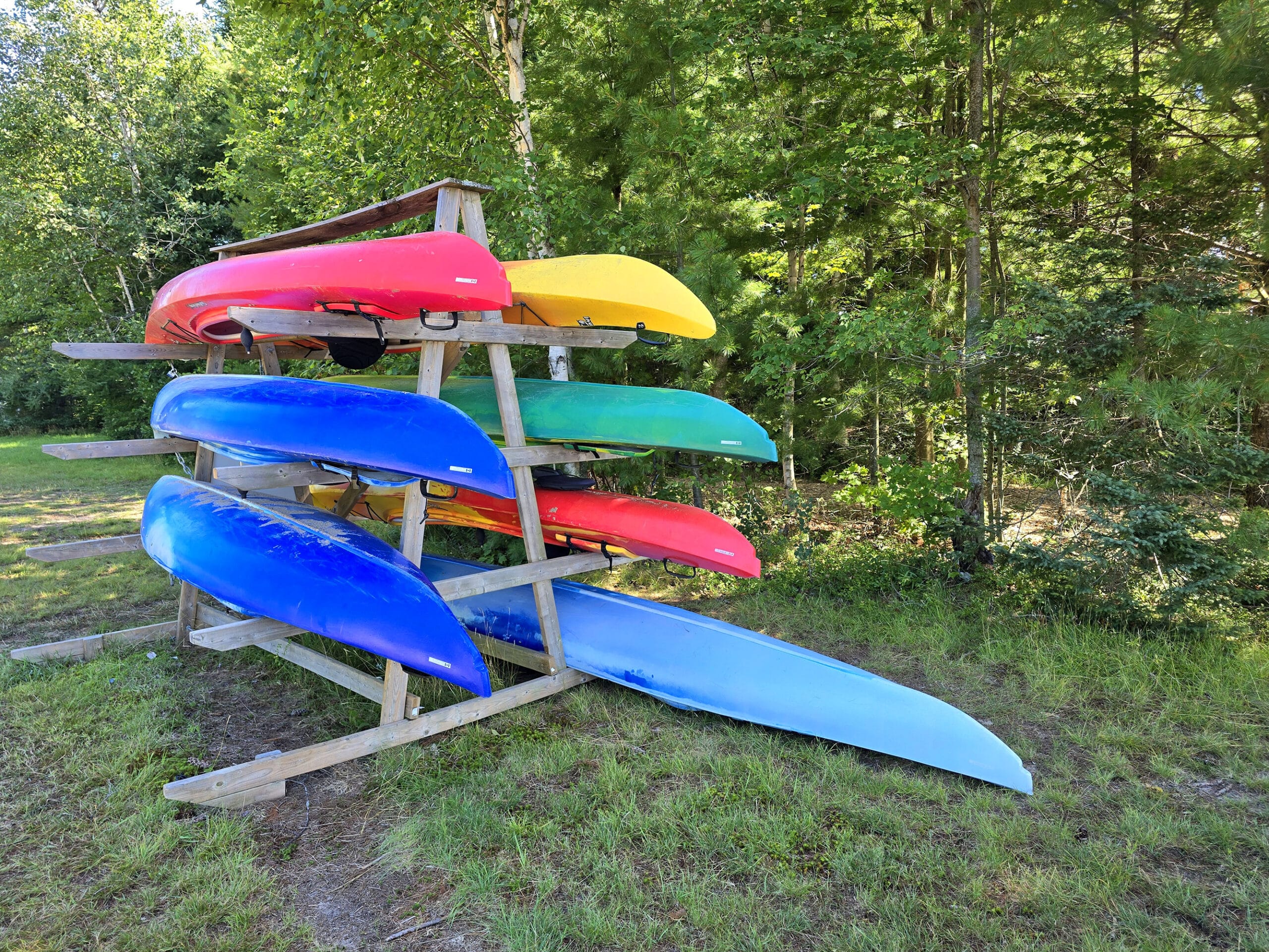 A canoe rack loaded with colourful canoes and kayaks.