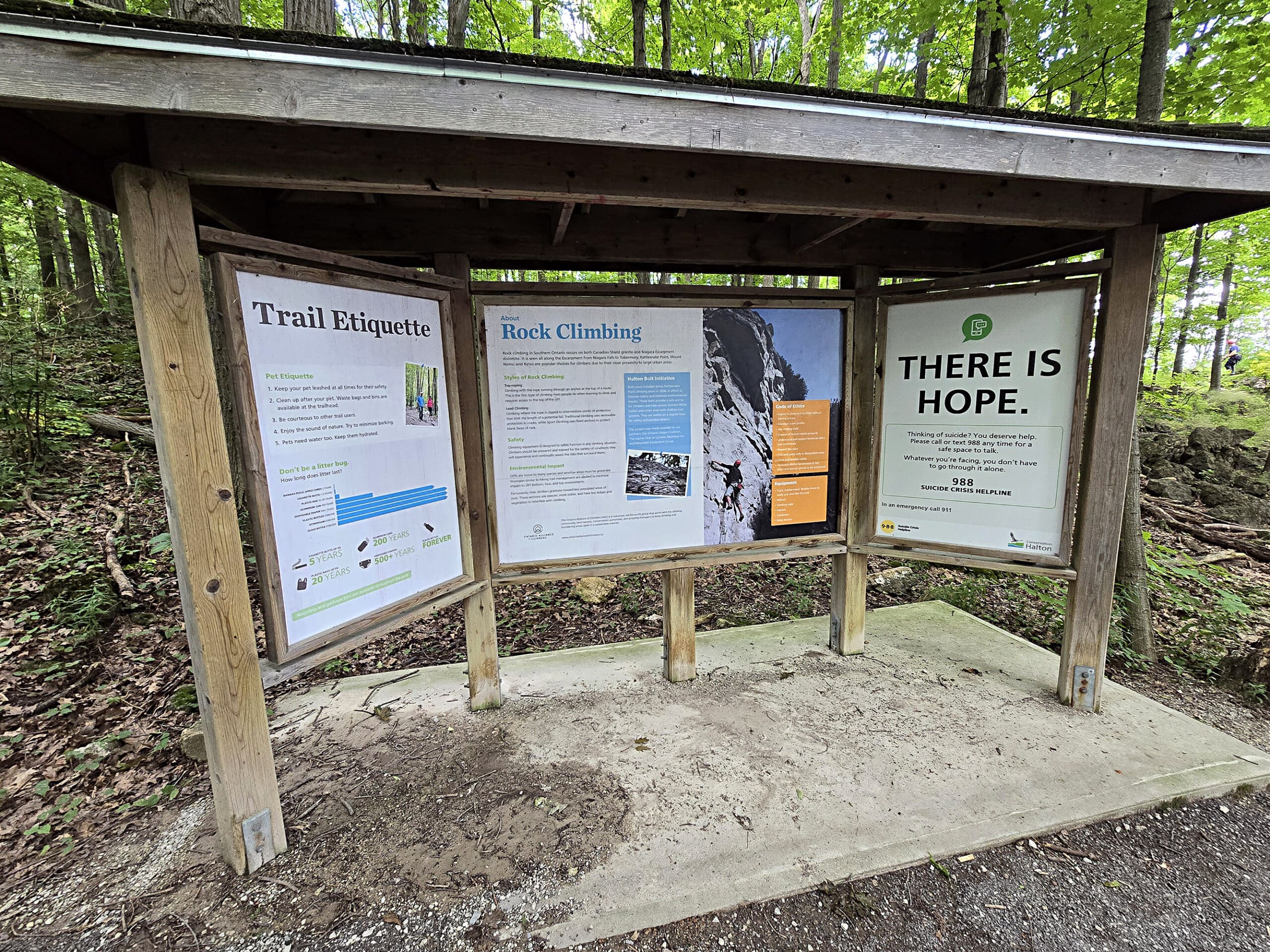 A large trail sign with information about rock climbing and suicide prevention.