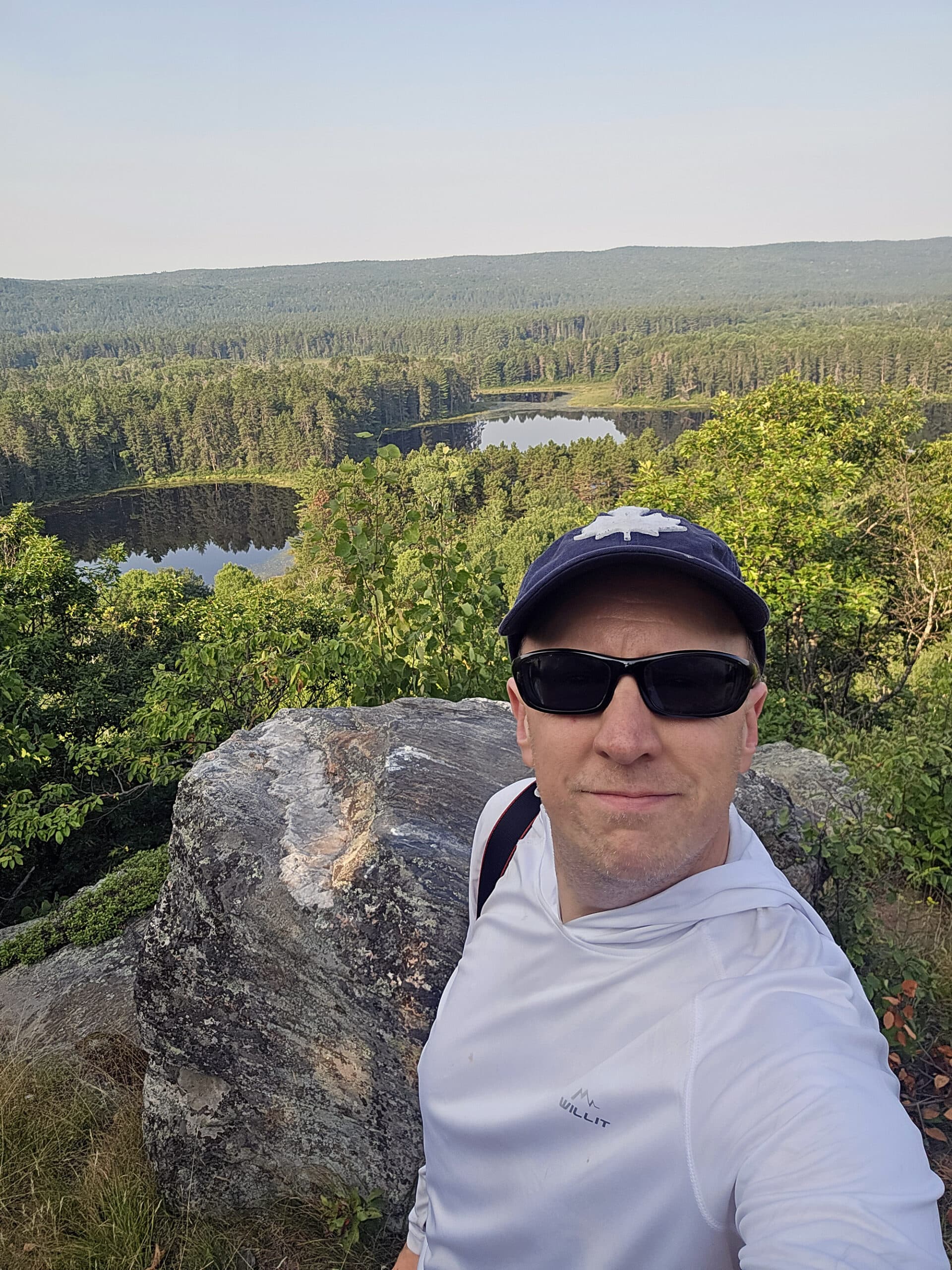 A middle aged white guy taking a selfie at the top of the Whispering Winds trail.