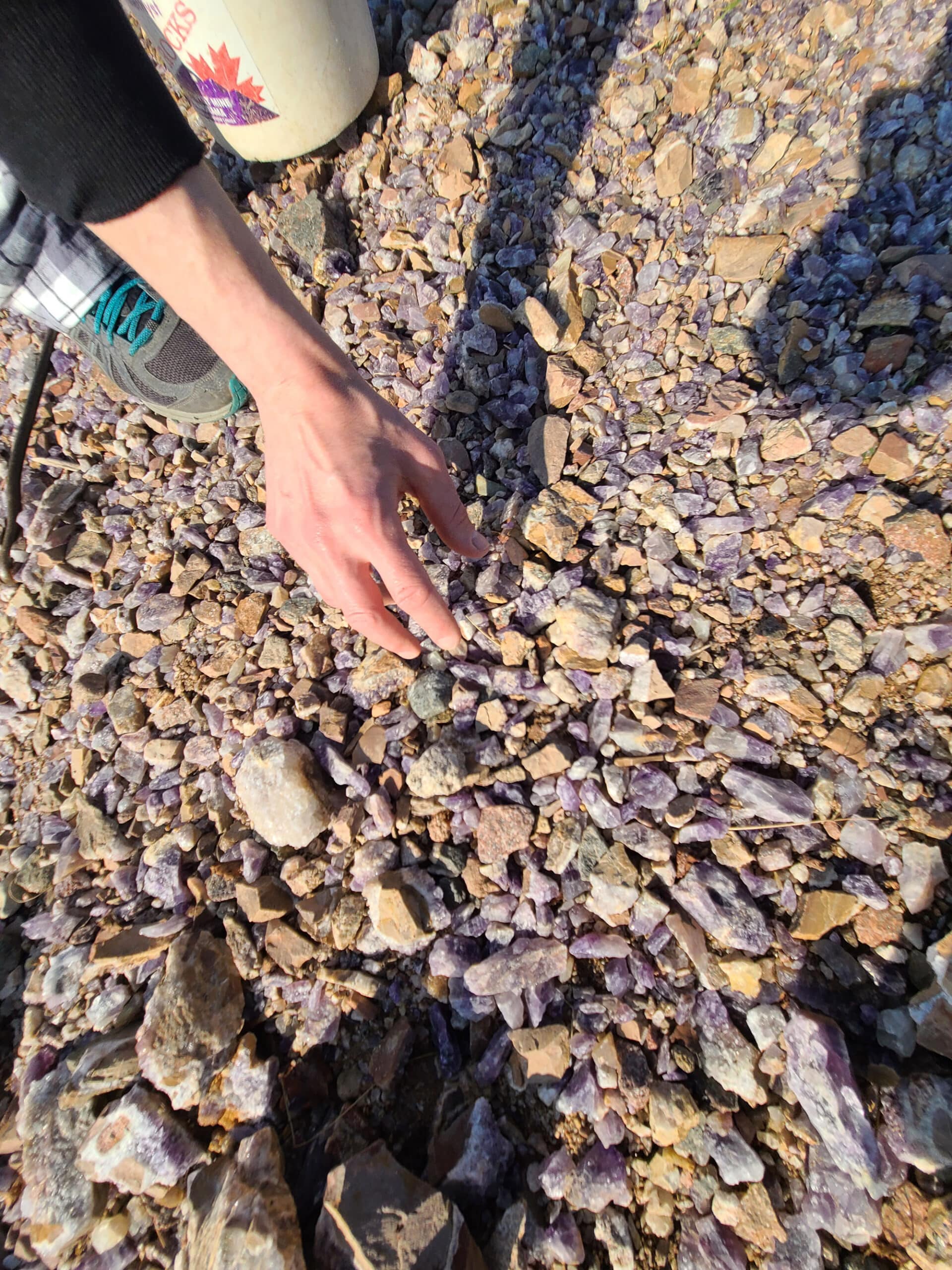 A hand picks an amethyst from a pile of them.