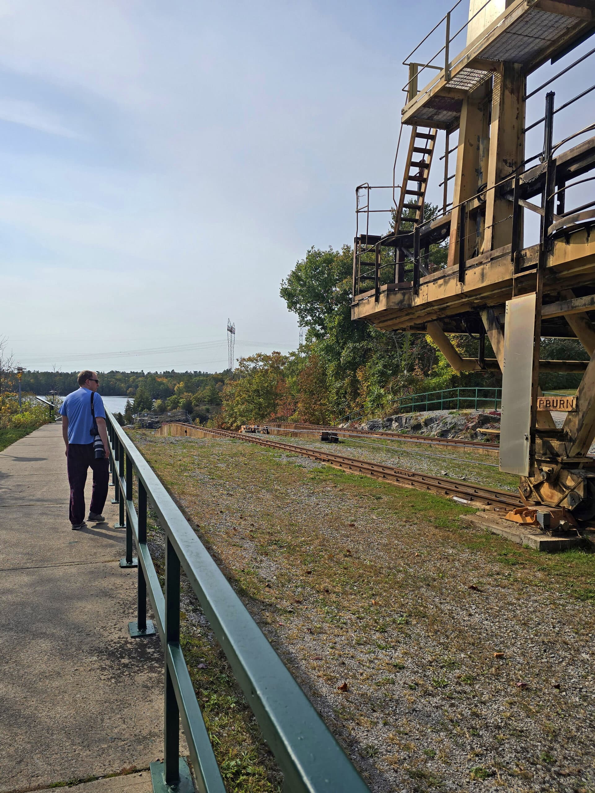 A middle aged white man walking along the big chute marine railway, looking at the carriage.