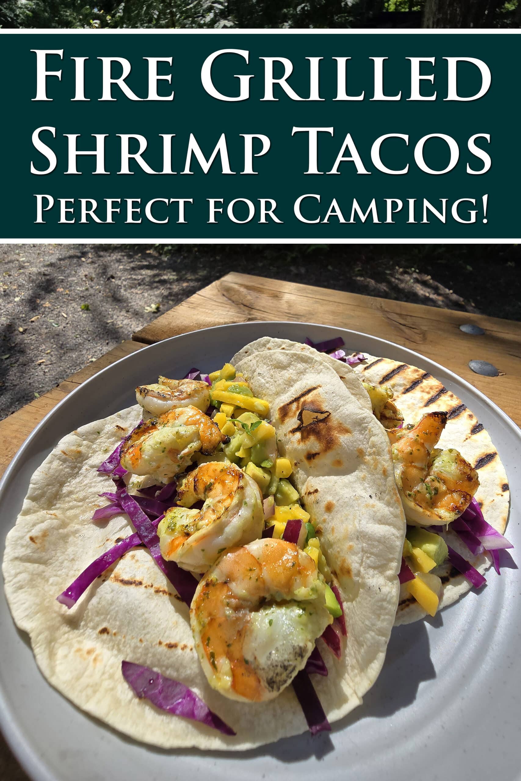 Two tacos with large grilled shrimp and mango salsa on a camping table. Overlaid text says campfire grilled shrimp tacos.