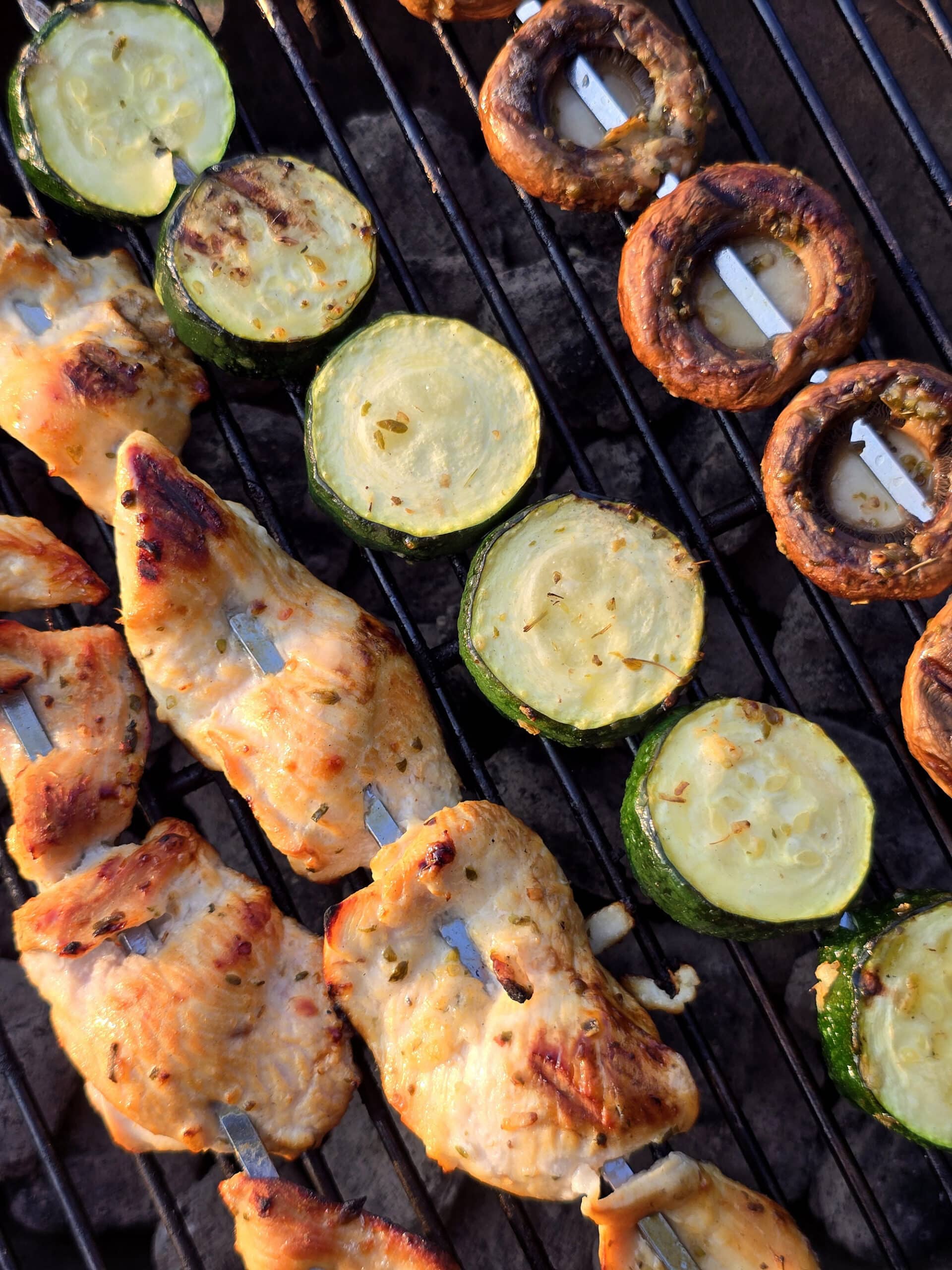 Mediterranean Chicken Kebabs  with skewers of zucchini and mushrooms on a charcoal grill.