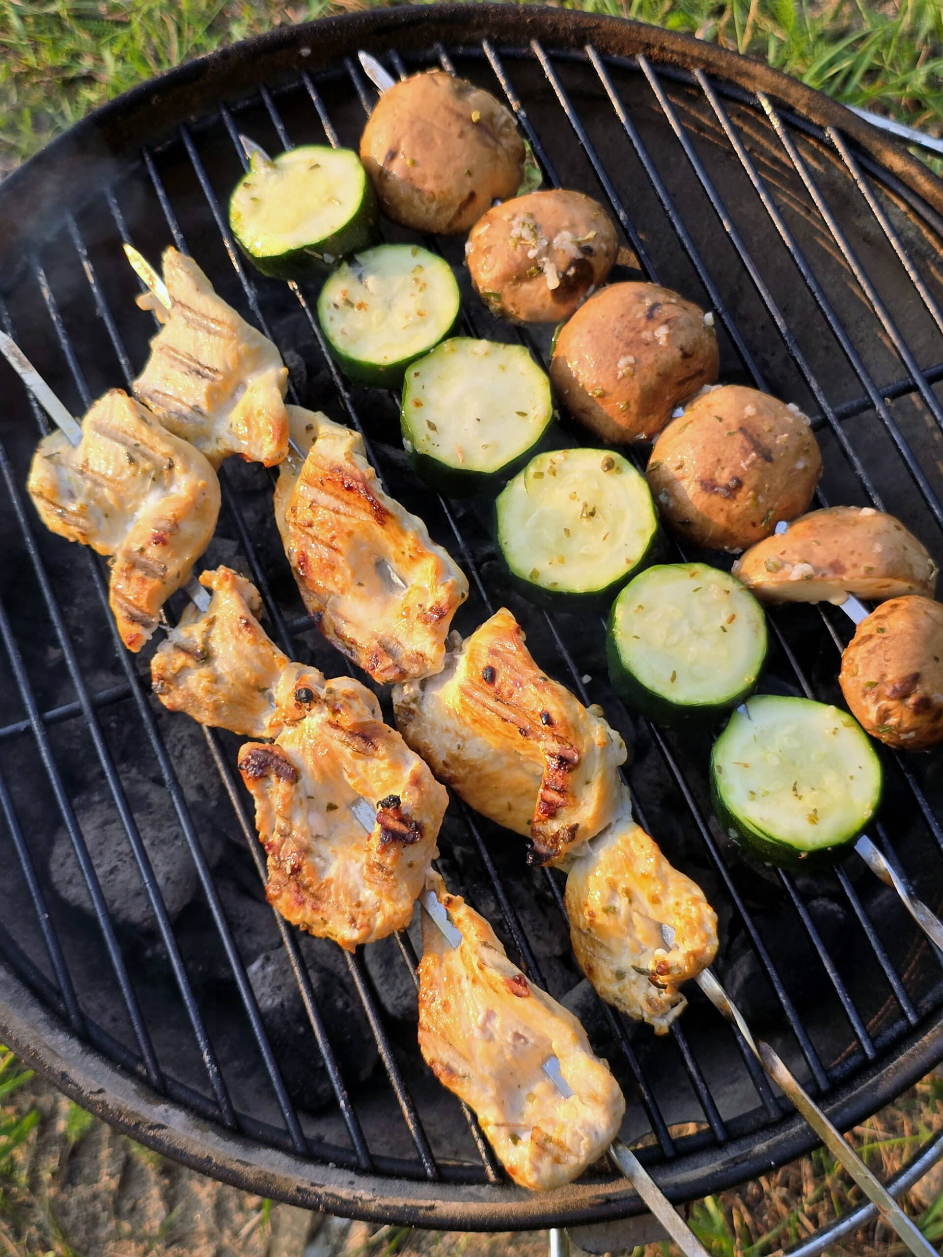 Mediterranean Chicken Kebabs  with skewers of zucchini and mushrooms on a charcoal grill.