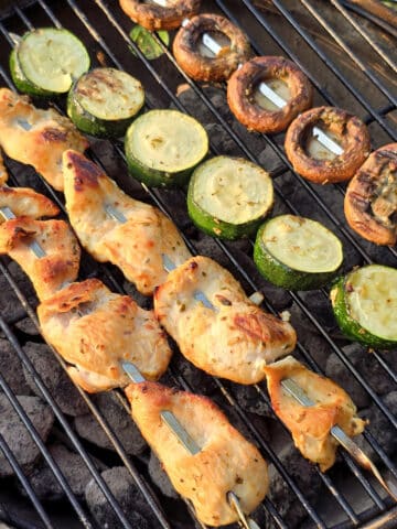 Mediterranean Chicken Kebabs with skewers of zucchini and mushrooms on a grill.