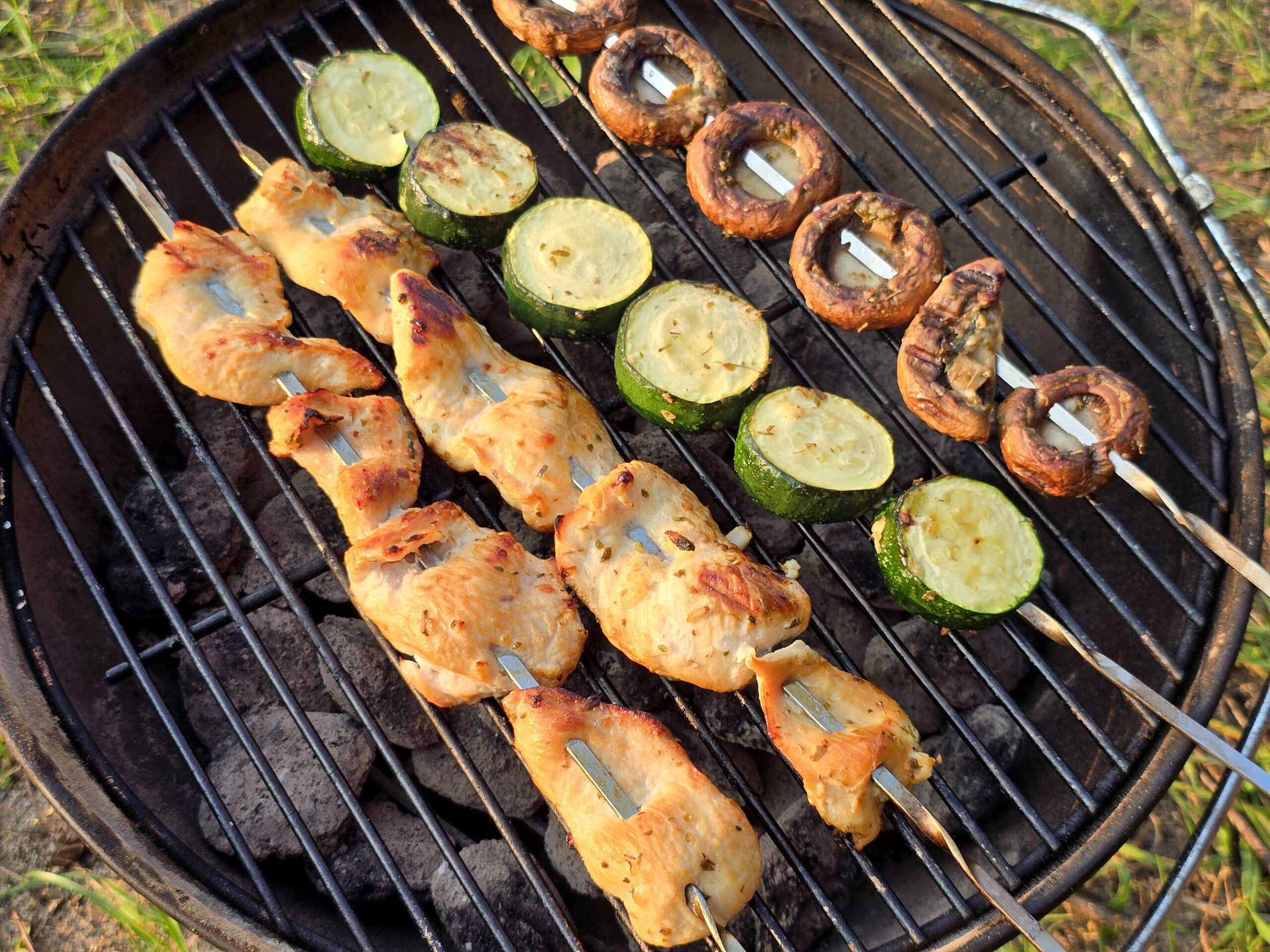 Mediterranean Chicken Kebabs  with skewers of zucchini and mushrooms on a grill.