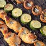 Mediterranean Chicken Kebabs with skewers of zucchini and mushrooms on a grill.