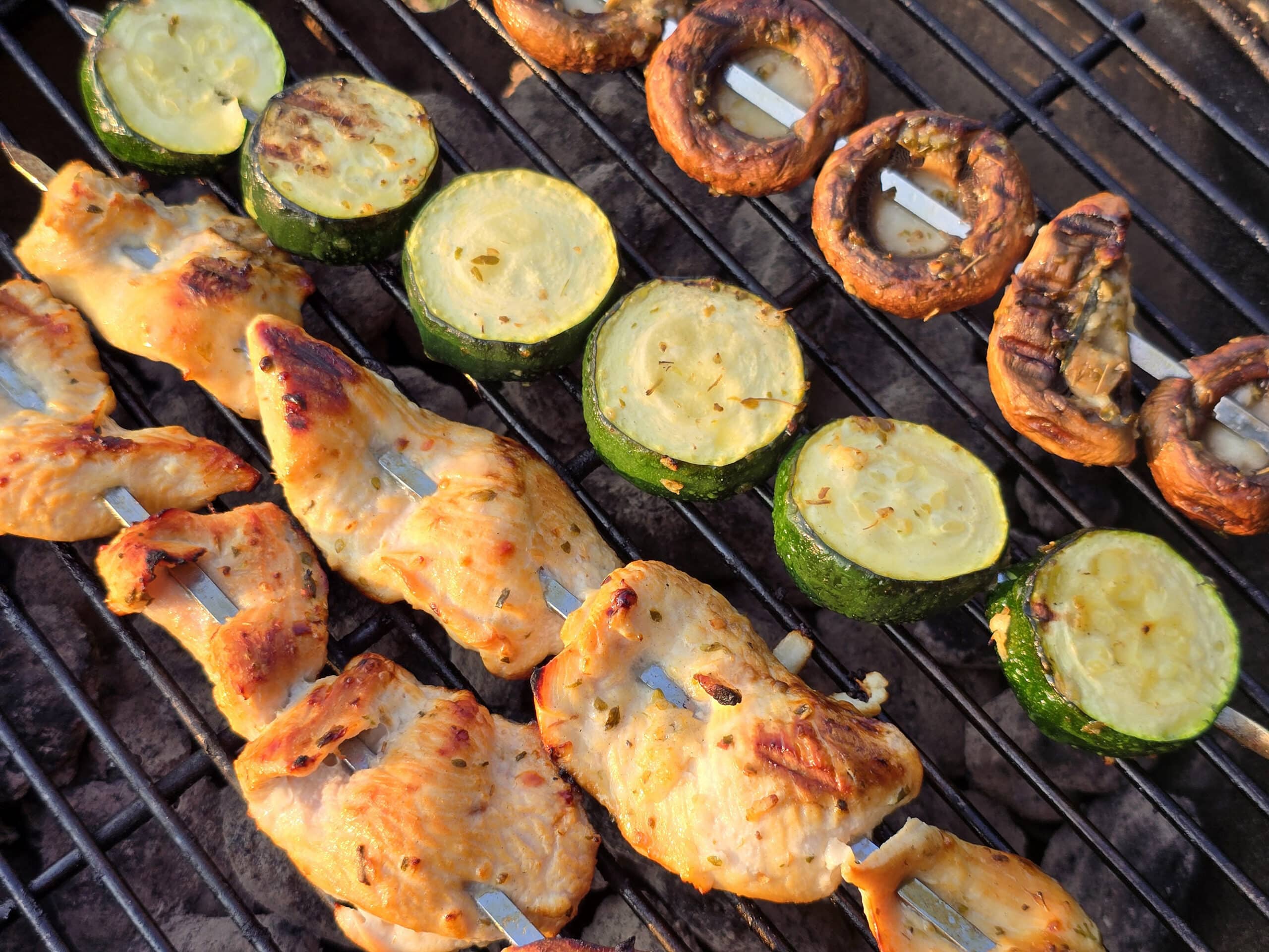 Mediterranean Chicken Kebabs  with skewers of zucchini and mushrooms on a grill.