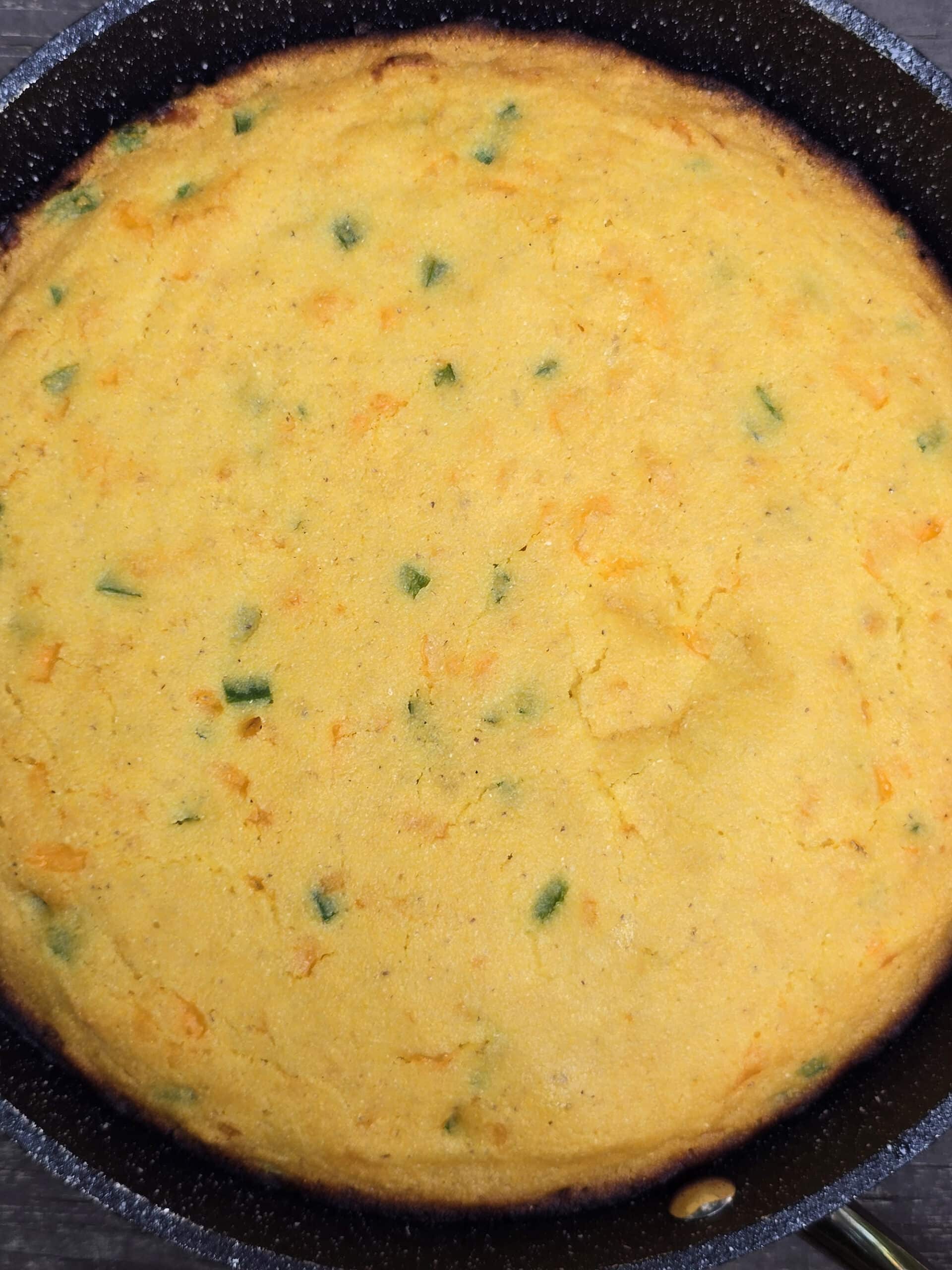 A pan of cheddar jalapeno cornbread on a picnic table.