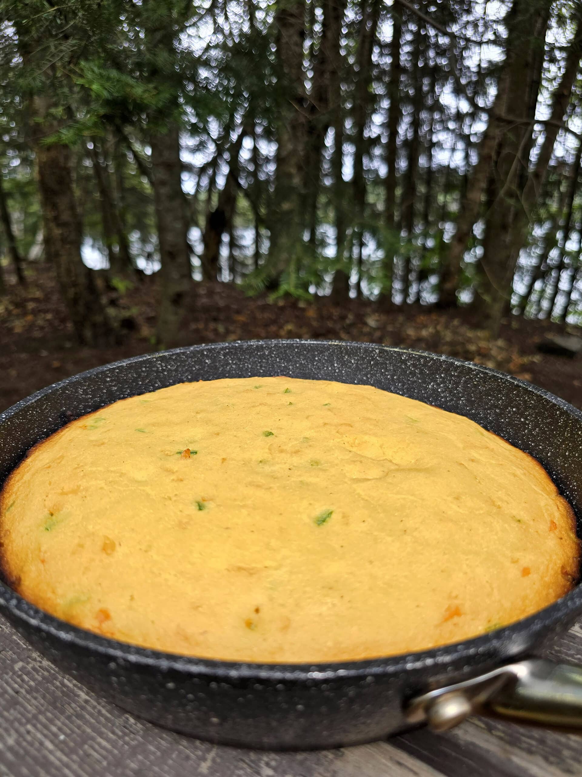 A pan of cheesy jalapeno cornbread on a picnic table.