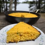 A pan and a slice of jalapeno cheddar cornbread on a picnic table.