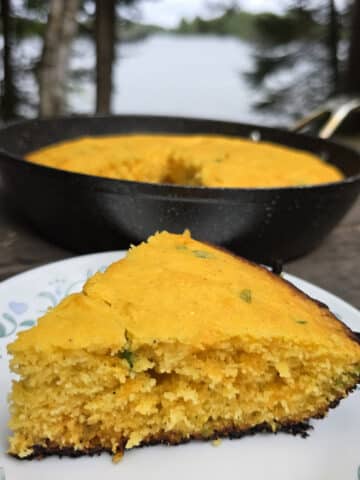 A pan and a slice of jalapeno cheddar cornbread on a picnic table.