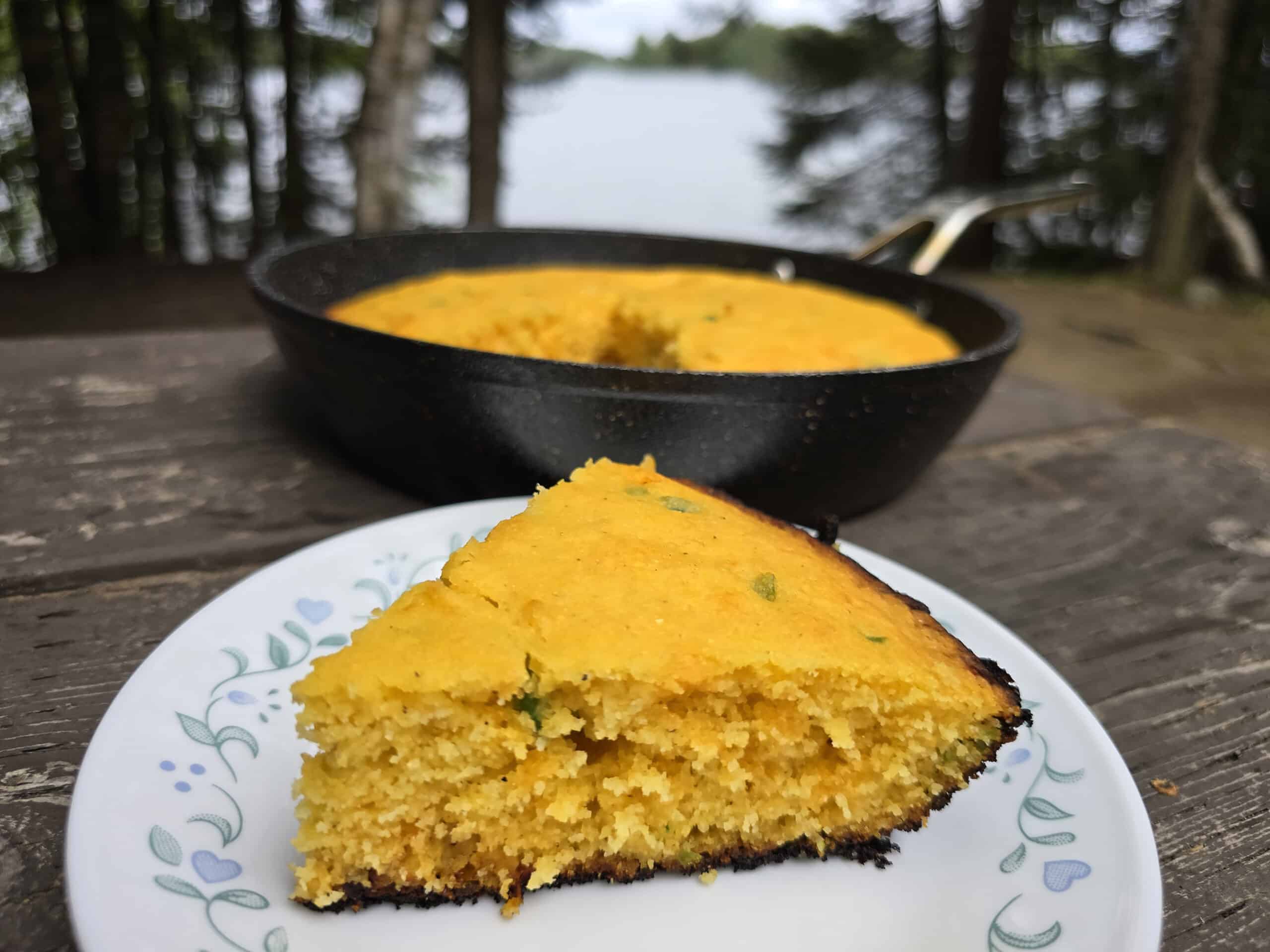 A pan and a slice of jalapeno cheddar cornbread on a picnic table.