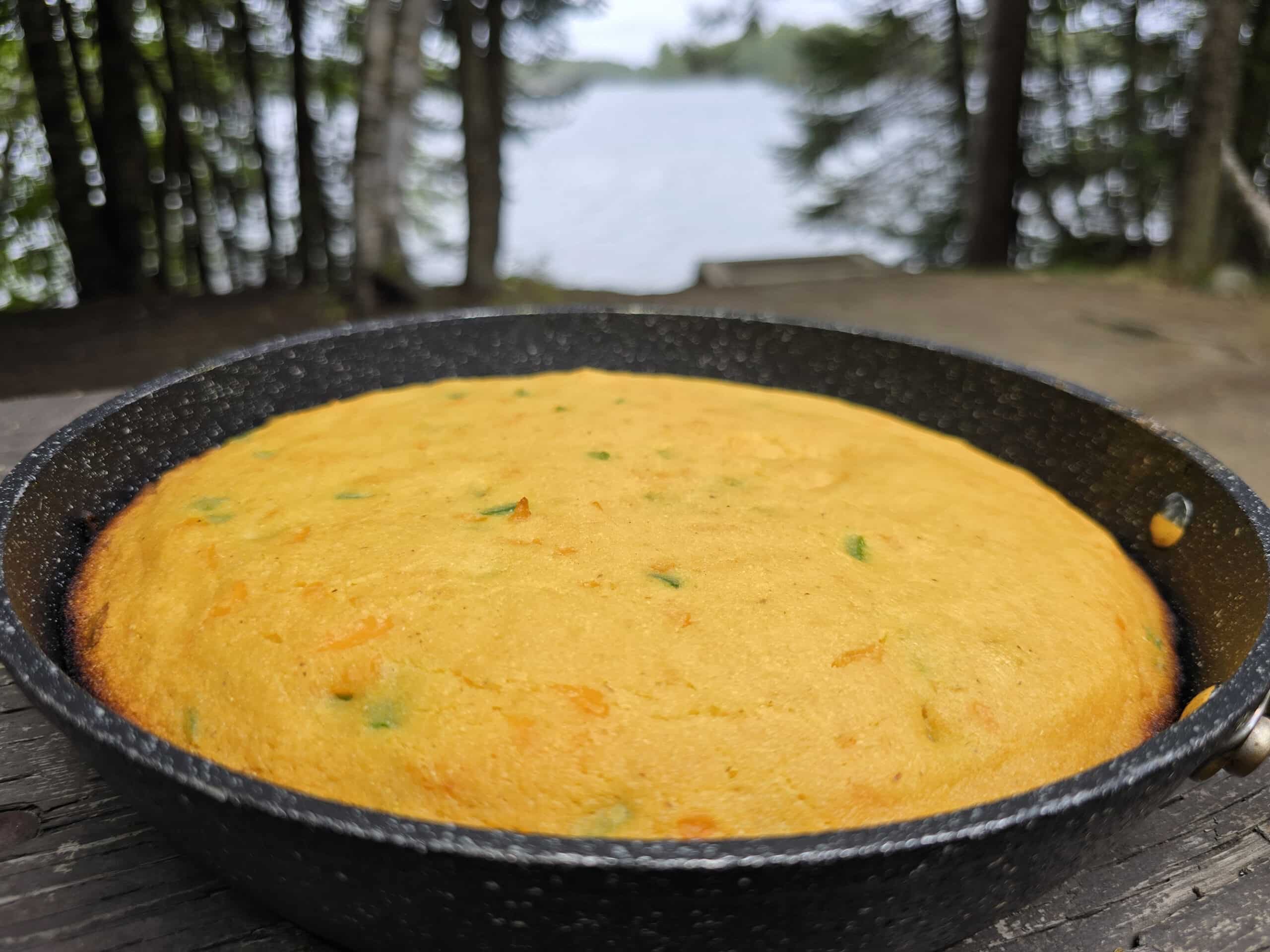 A pan of cheddar jalapeno cornbread on a picnic table.