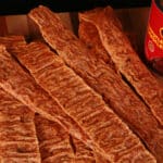 Chipotle chicken jerky strips on a wooden cutting board.