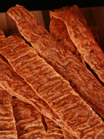 Chipotle chicken jerky strips on a wooden cutting board.