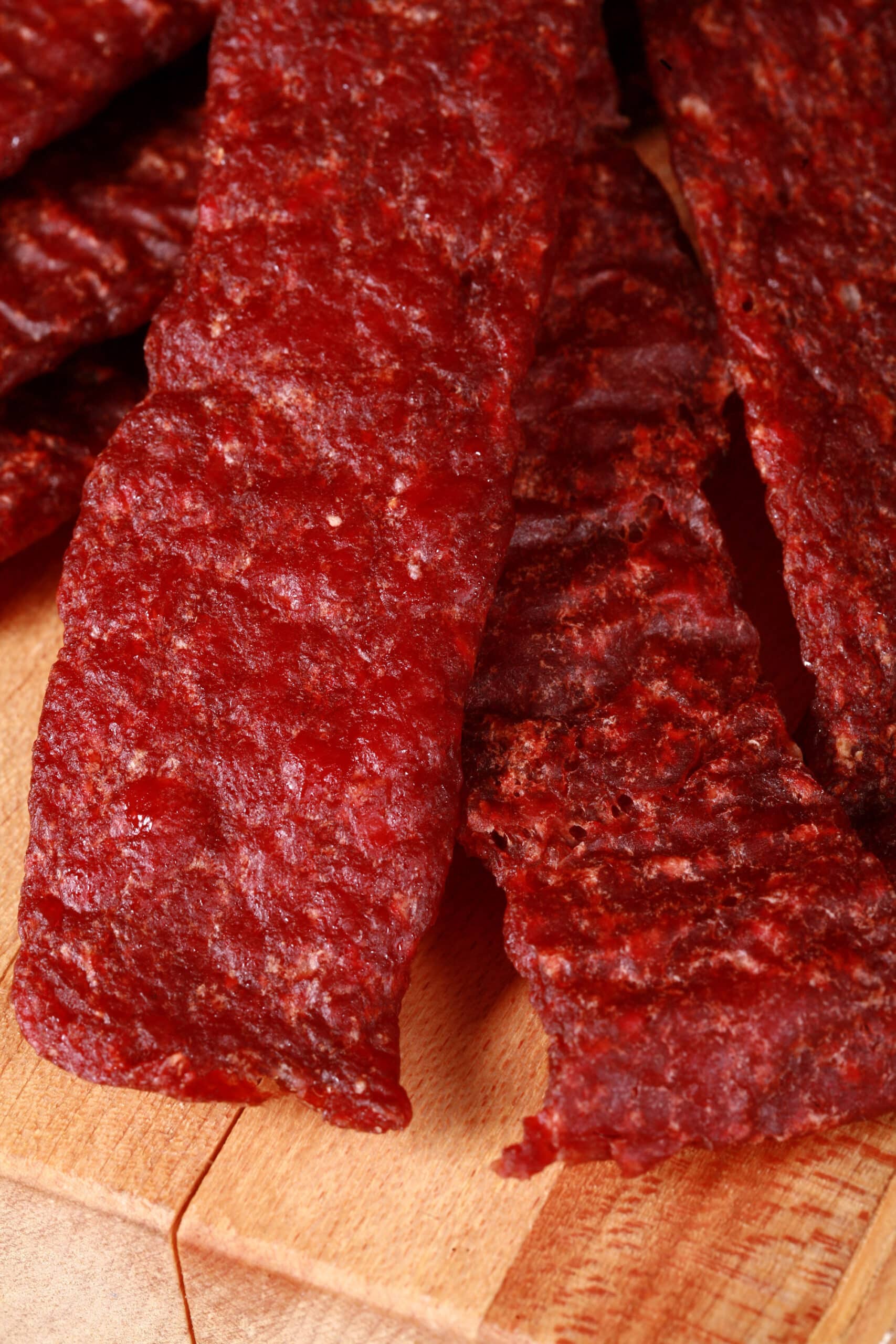 A pile of homemade beef jerky strips on a wooden cutting board.