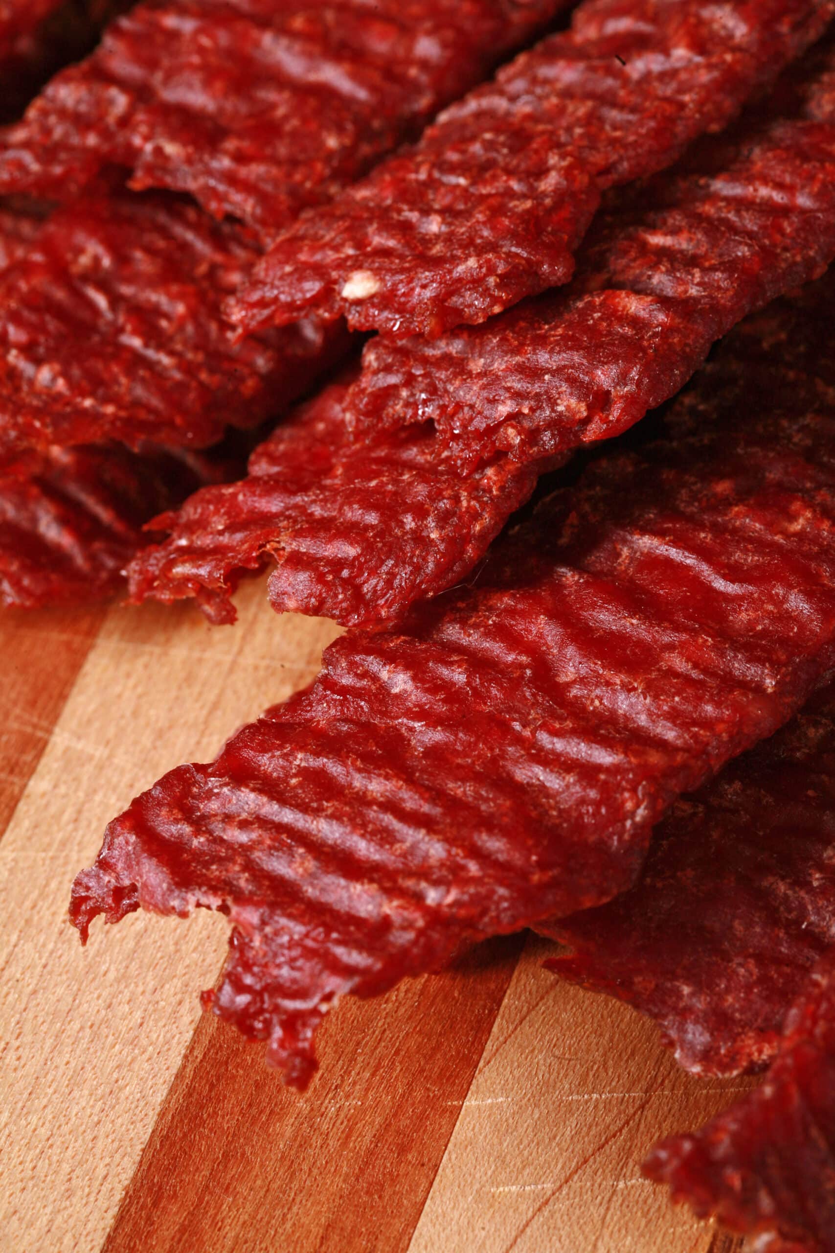 A pile of homemade beef jerky strips on a wooden cutting board.