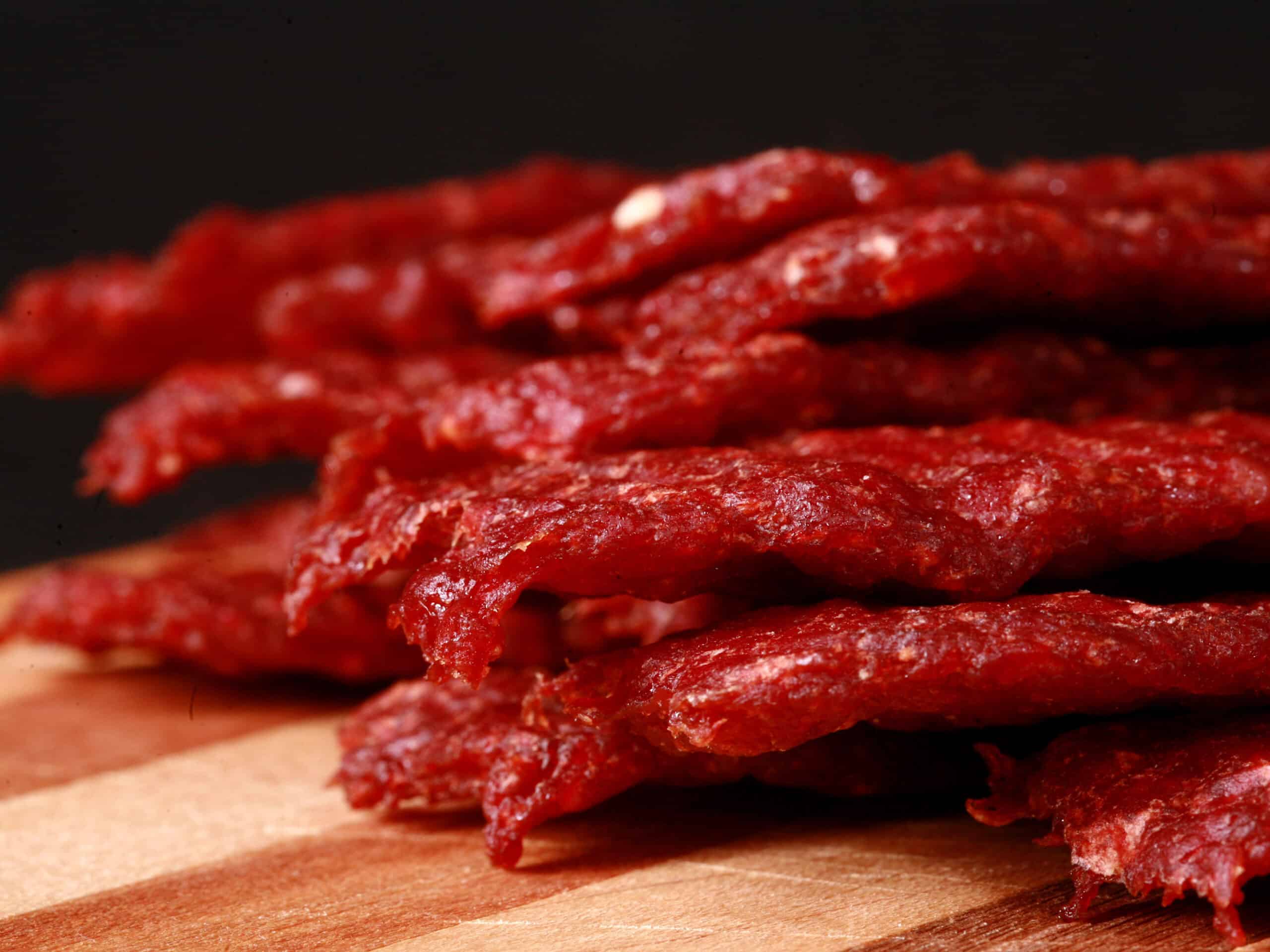 A pile of homemade beef jerky strips on a wooden cutting board.