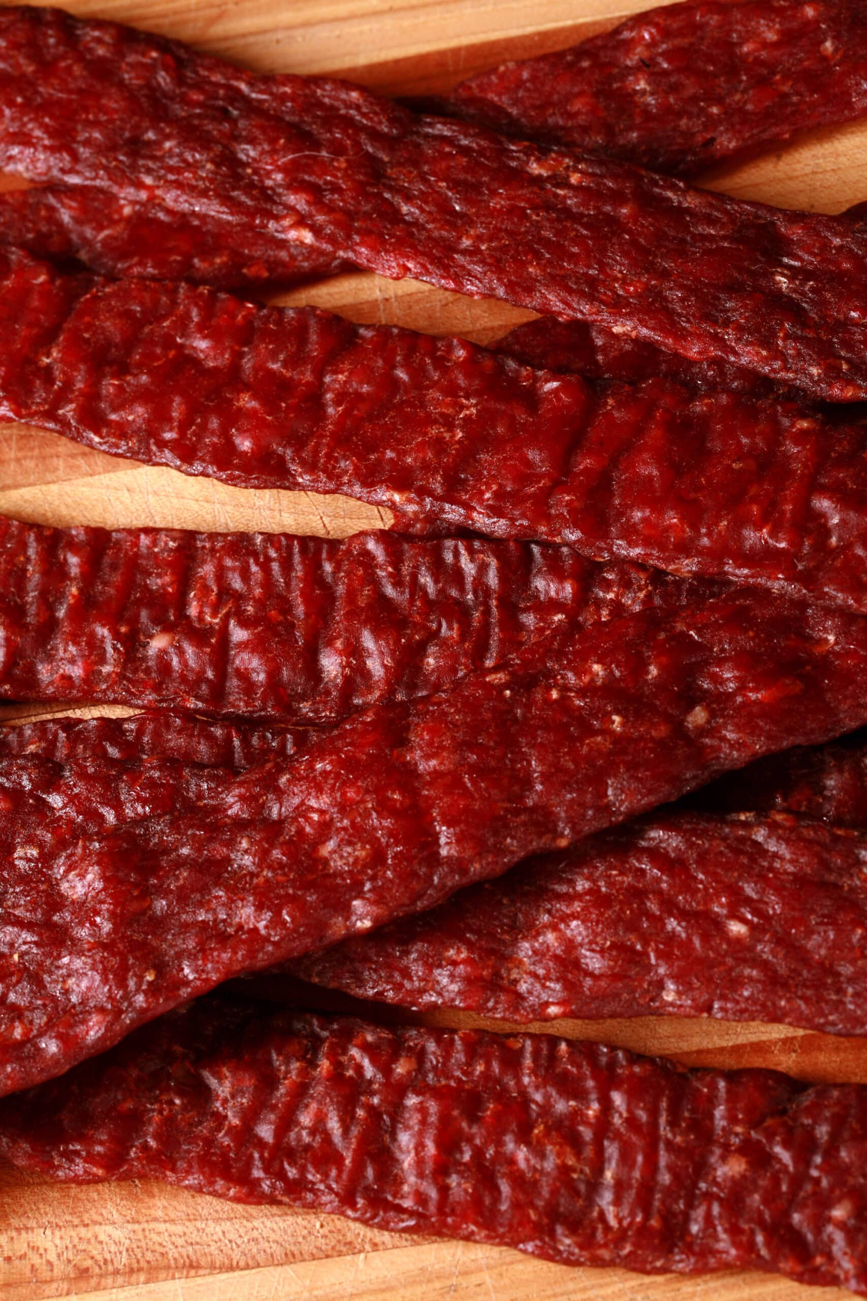 A pile of homemade ground venison jerky strips on a cutting board.