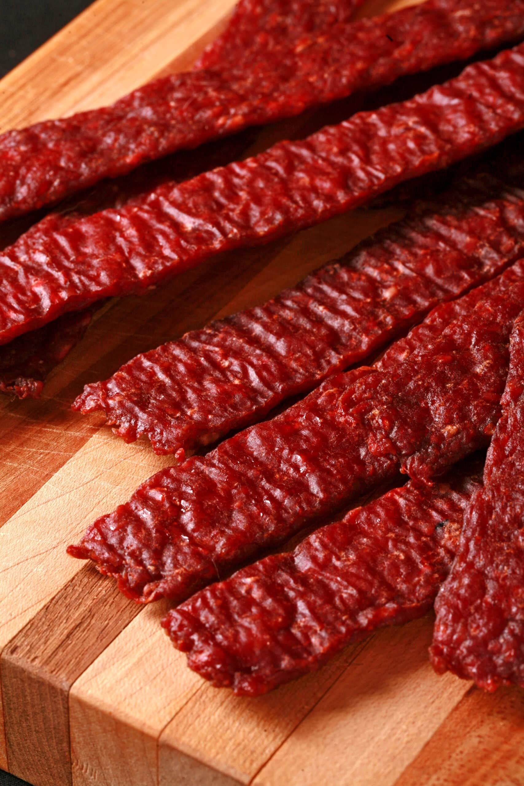 A pile of homemade venison jerky strips on a cutting board.