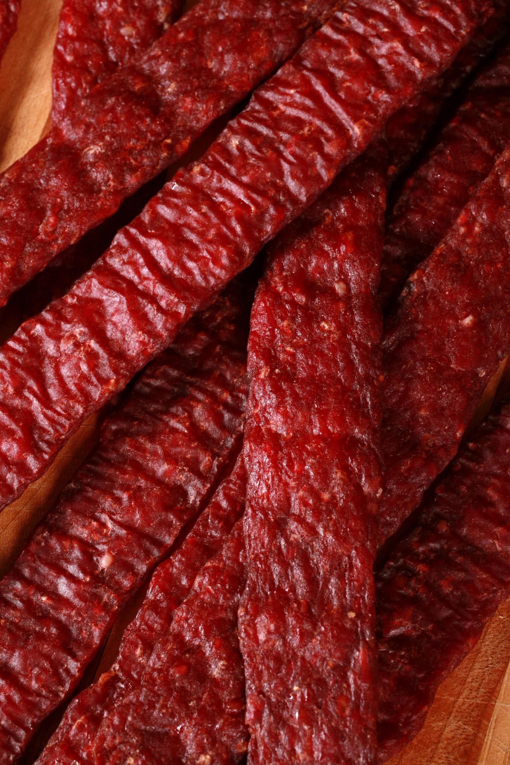 A pile of homemade ground venison jerky strips on a cutting board.