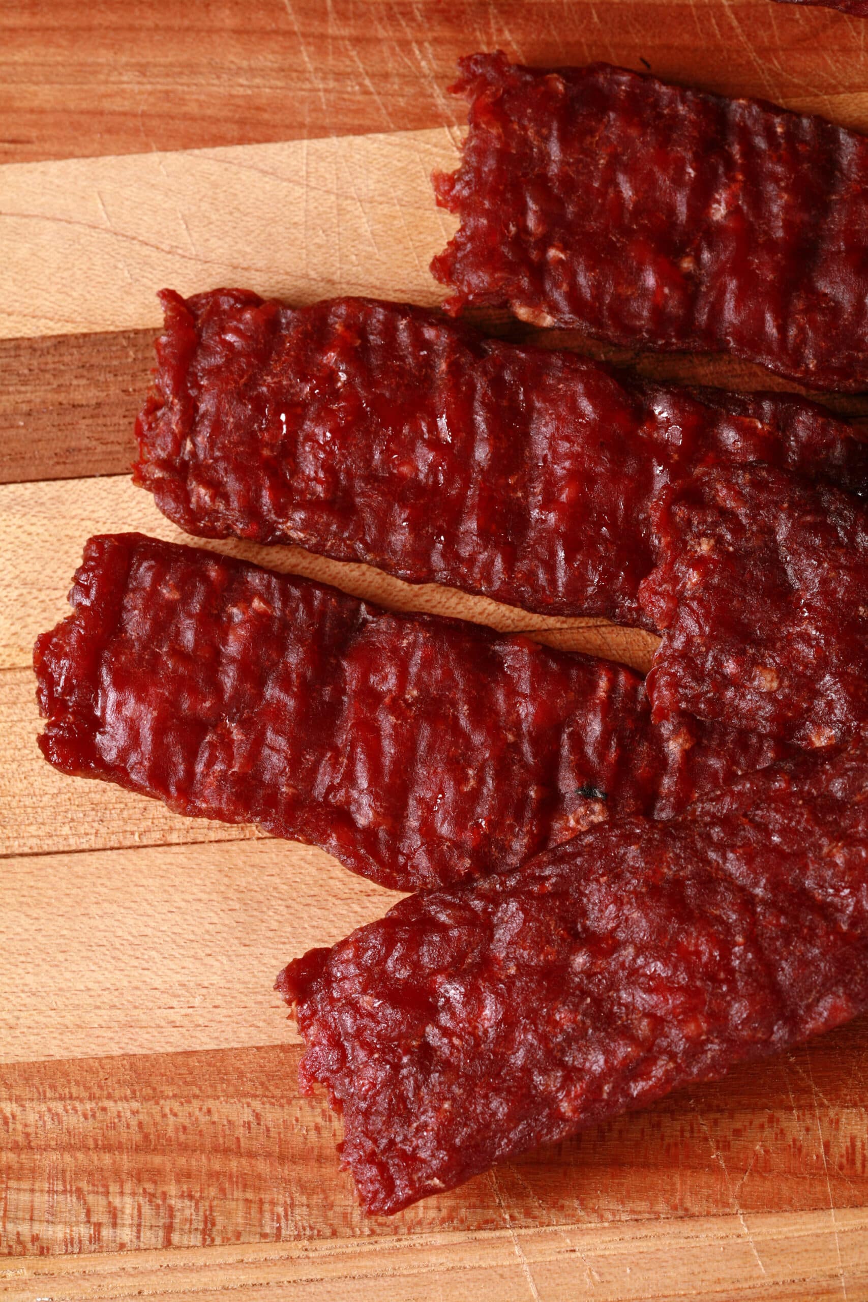 A pile of homemade venison jerky strips on a cutting board.