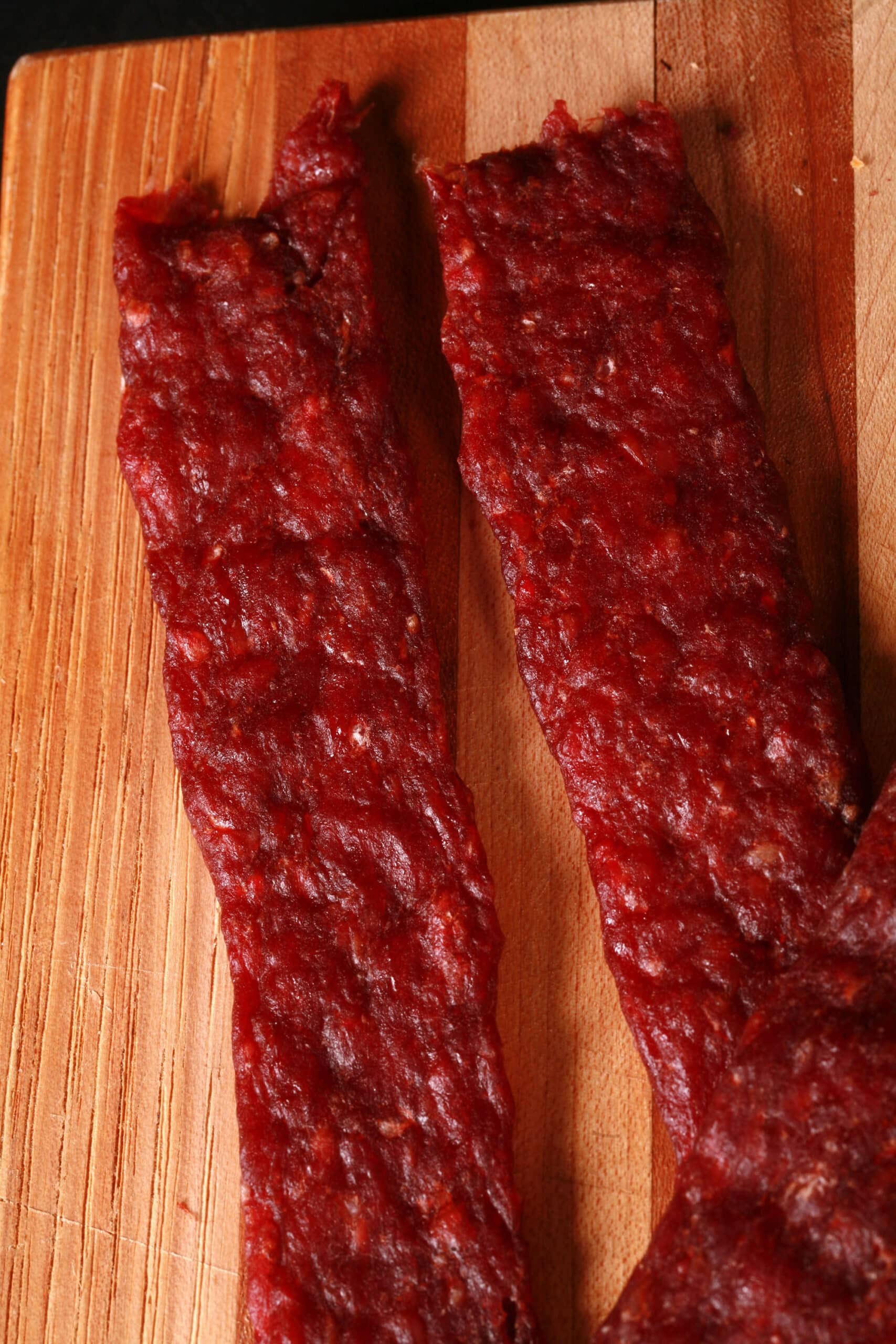 A pile of homemade ground venison jerky strips on a cutting board.