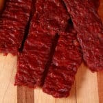 A pile of homemade venison jerky strips on a cutting board.