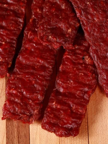 A pile of homemade venison jerky strips on a cutting board.