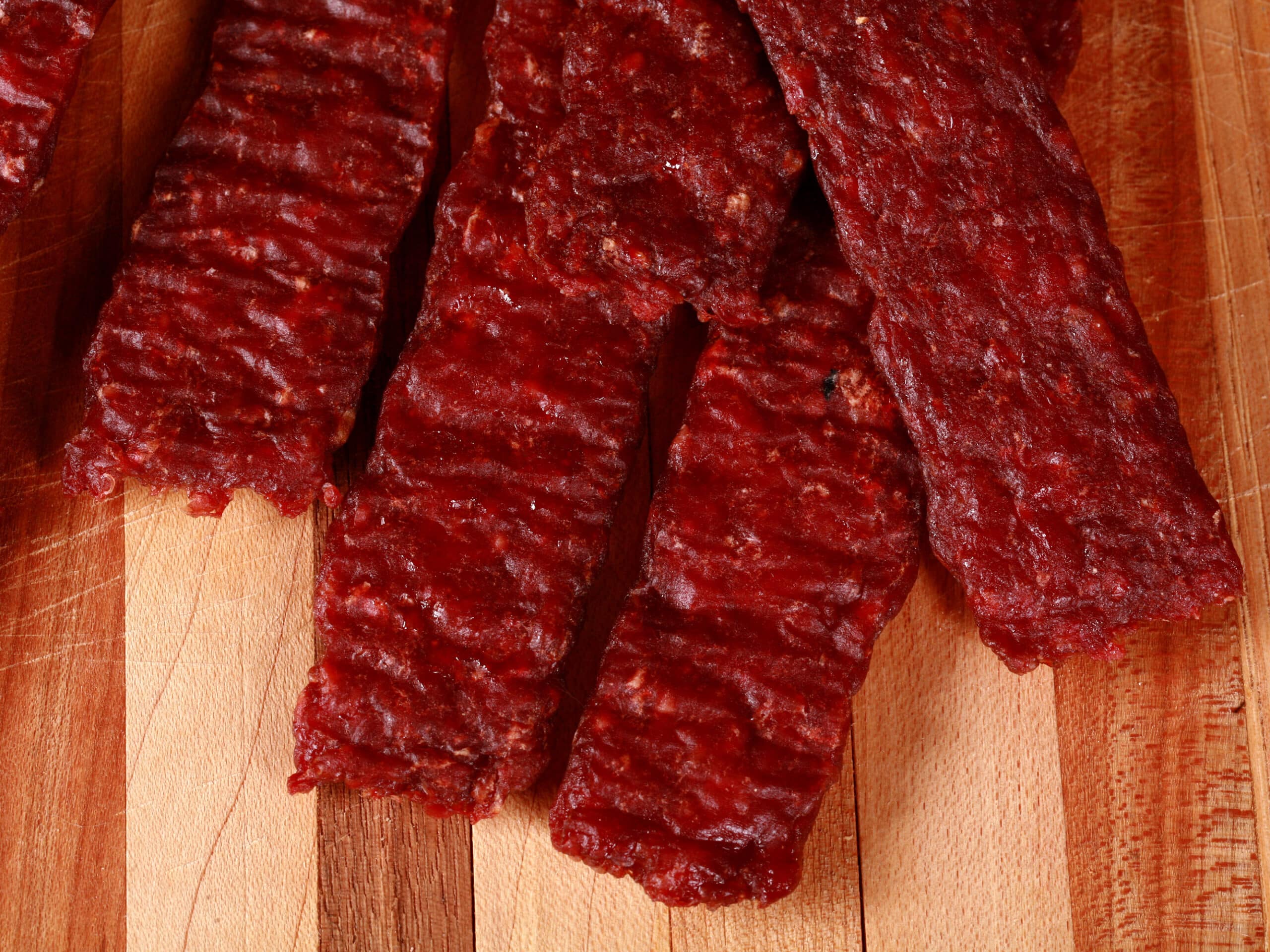 A pile of homemade venison jerky strips on a cutting board.