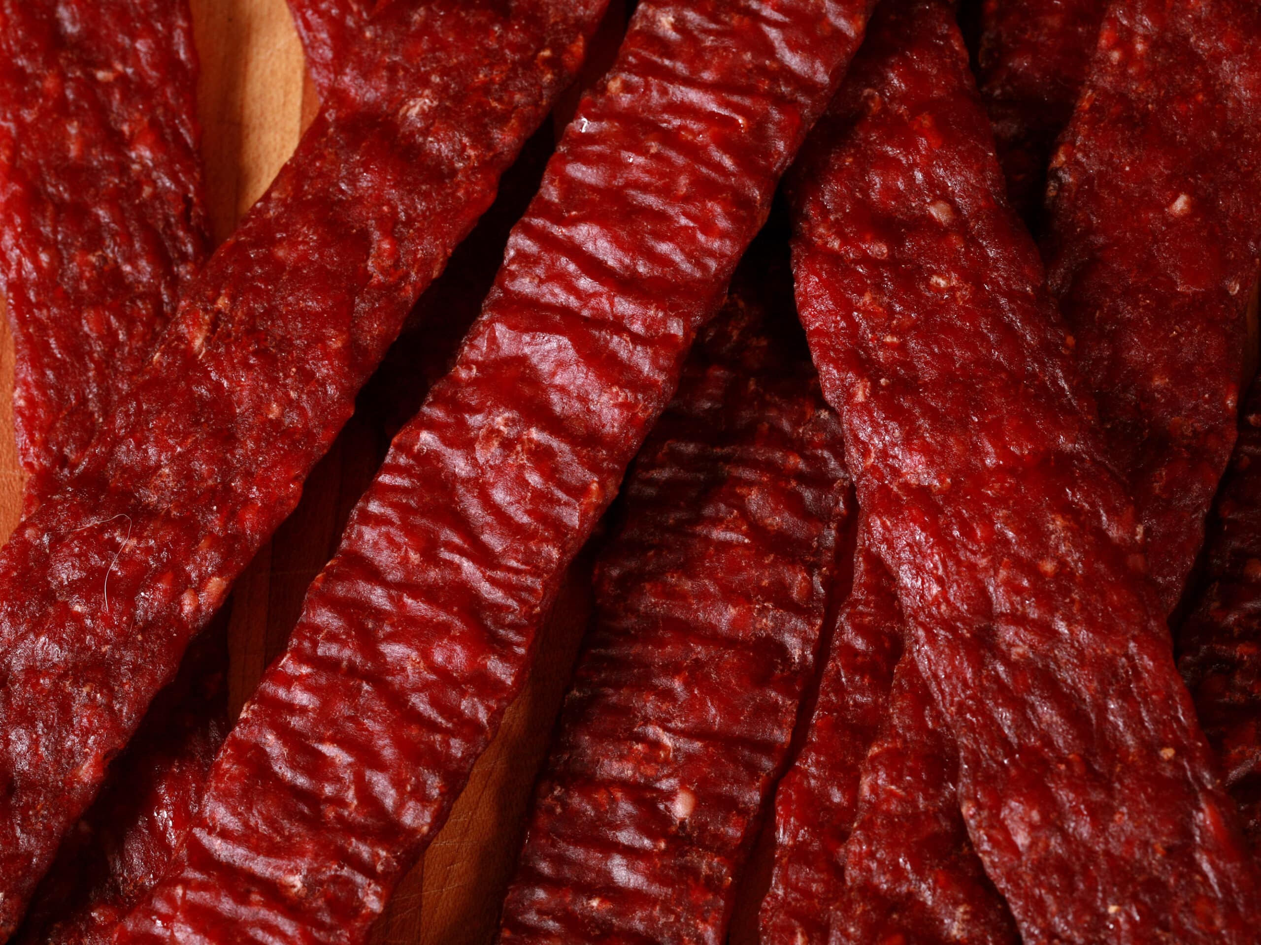 A pile of homemade ground venison jerky strips on a cutting board.