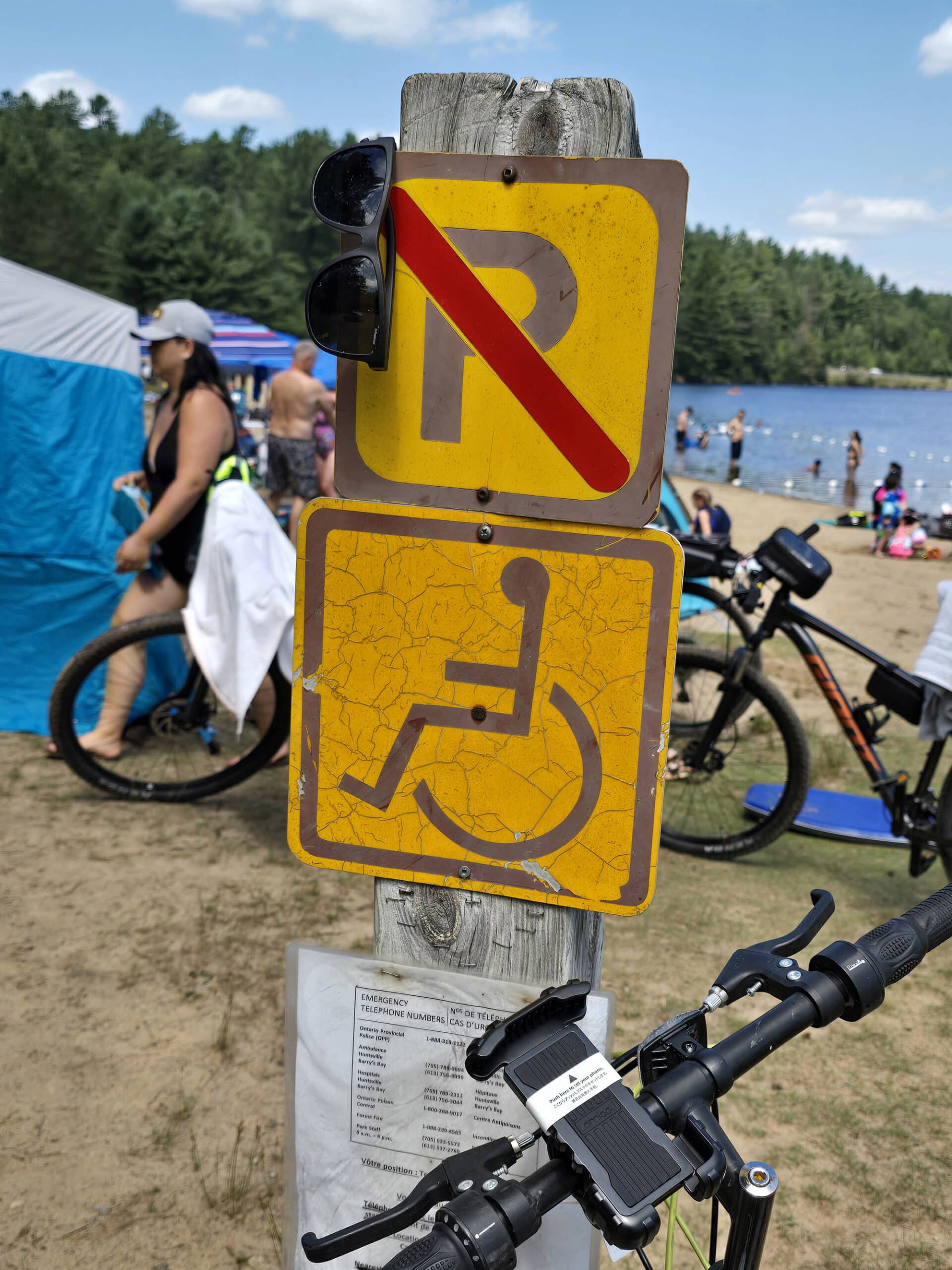 A  backwards accessible parking sign with a busy beach in the background.