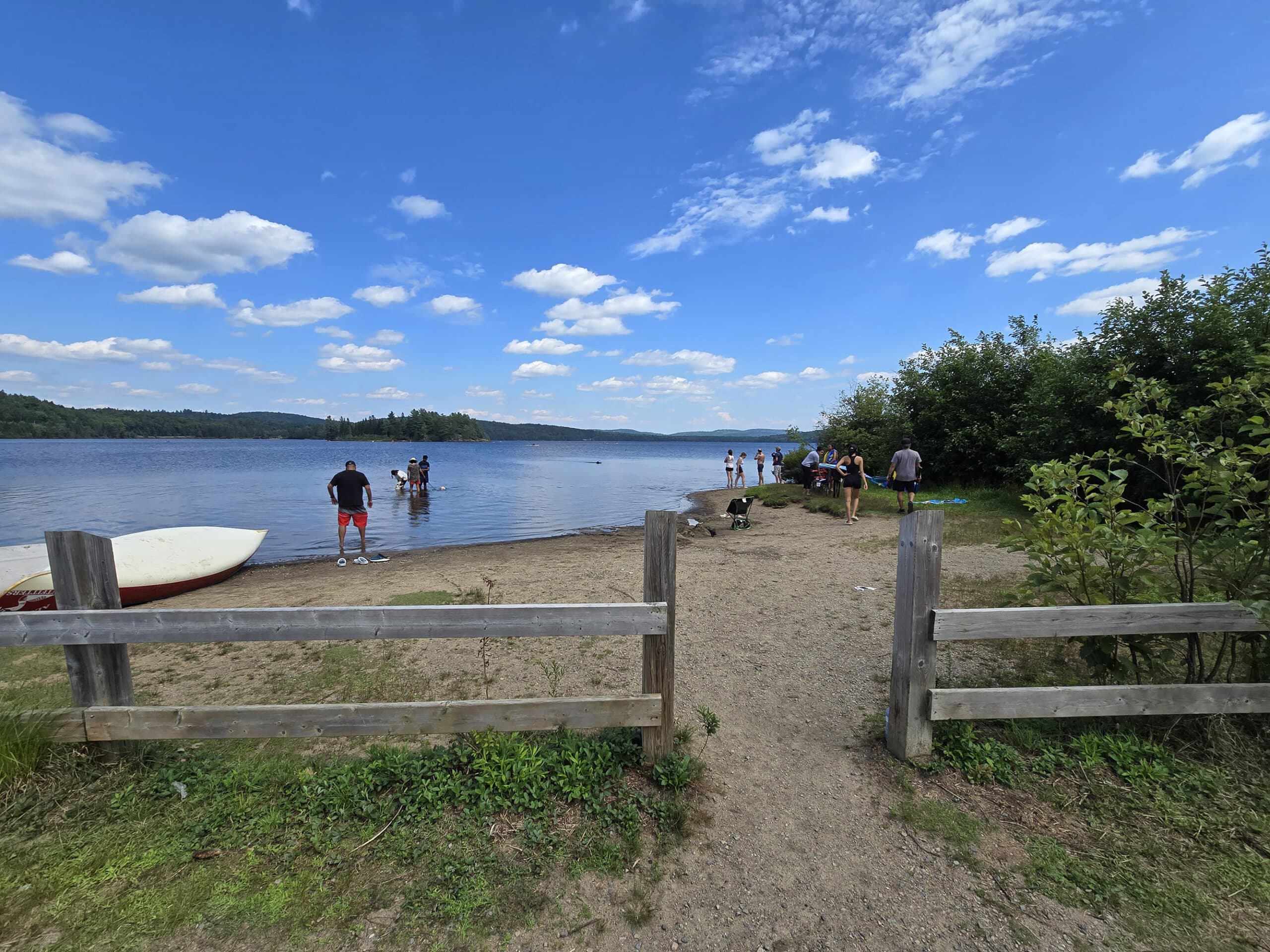 A small, partially fenced dog beach at Lake of Two Rivers Campground.