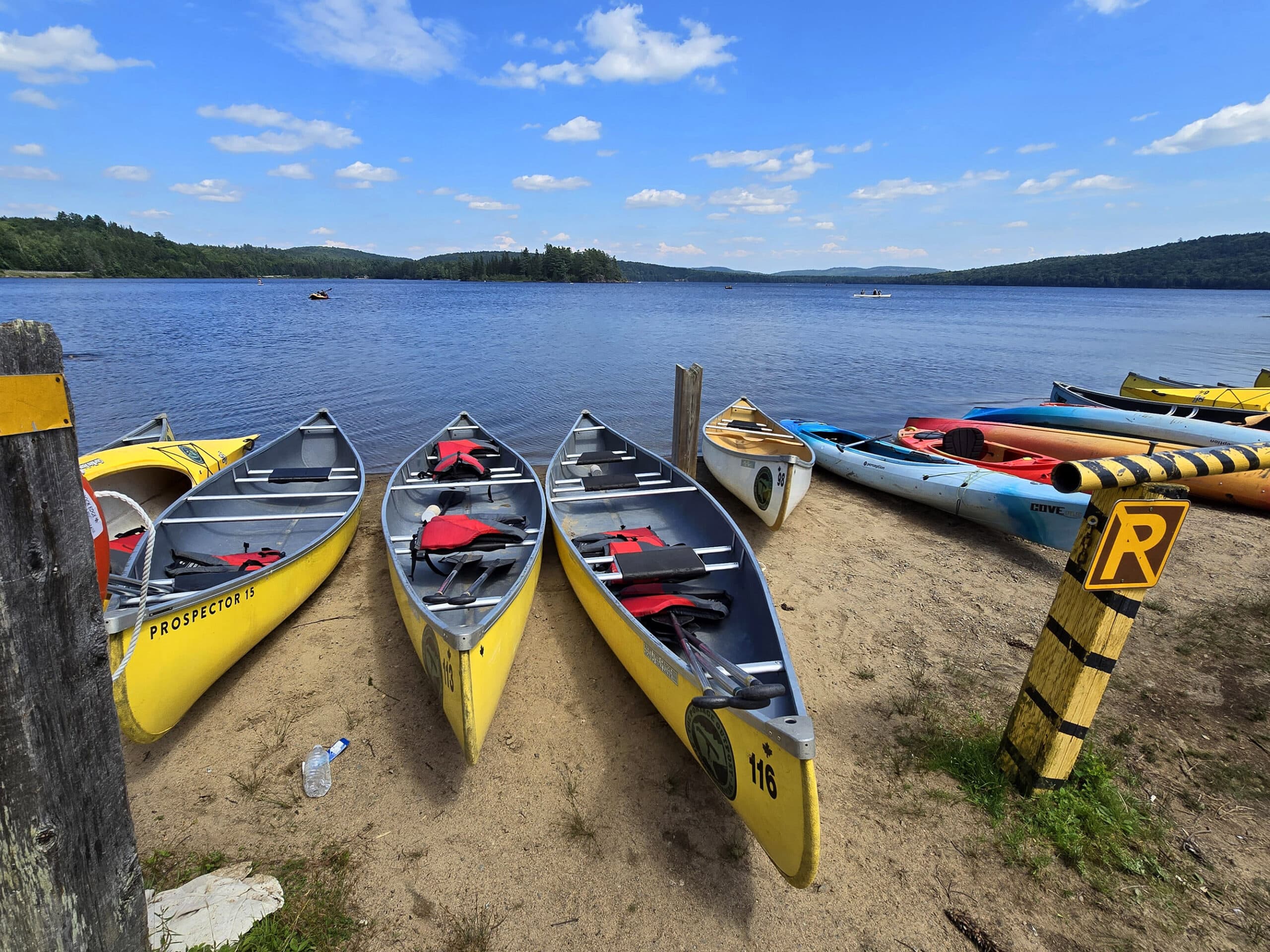 Several brightly coloured canoes on the shore at Lake of Two Rivers beach.