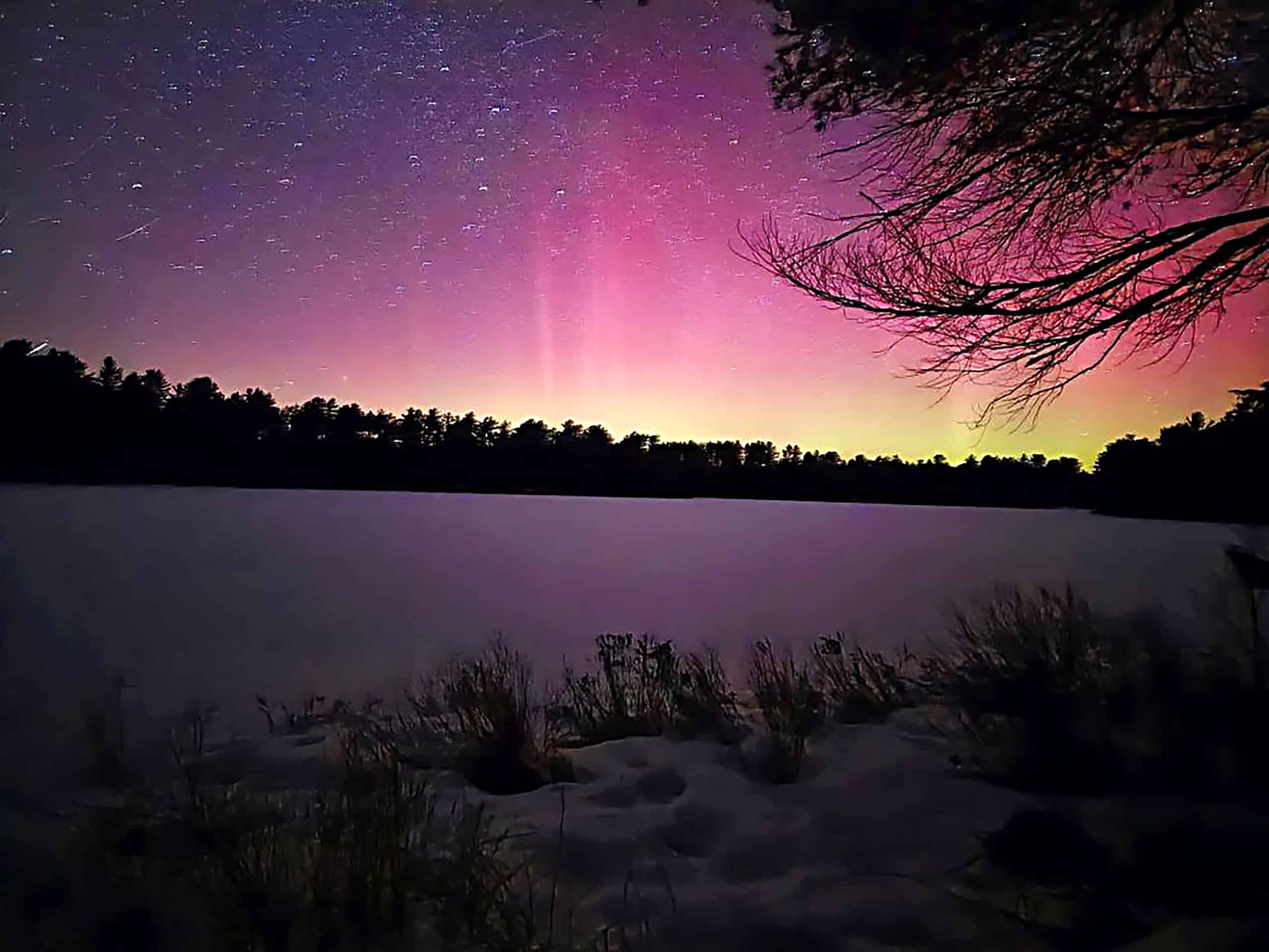 A pink and yellow aurora borealis over mew lake.