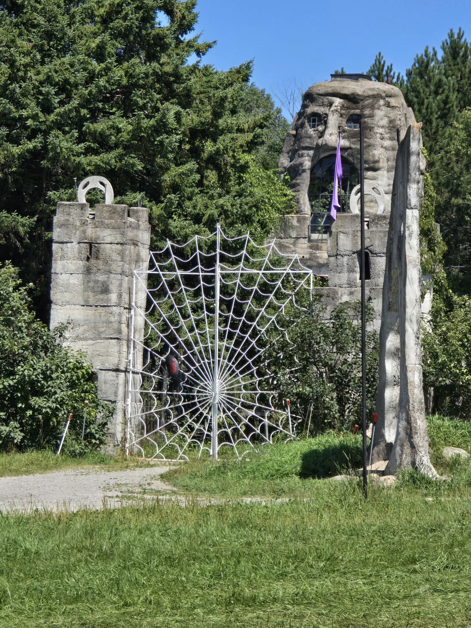 A tall spiderweb style gate, with a castle turret that looks like a creepy head behind it.